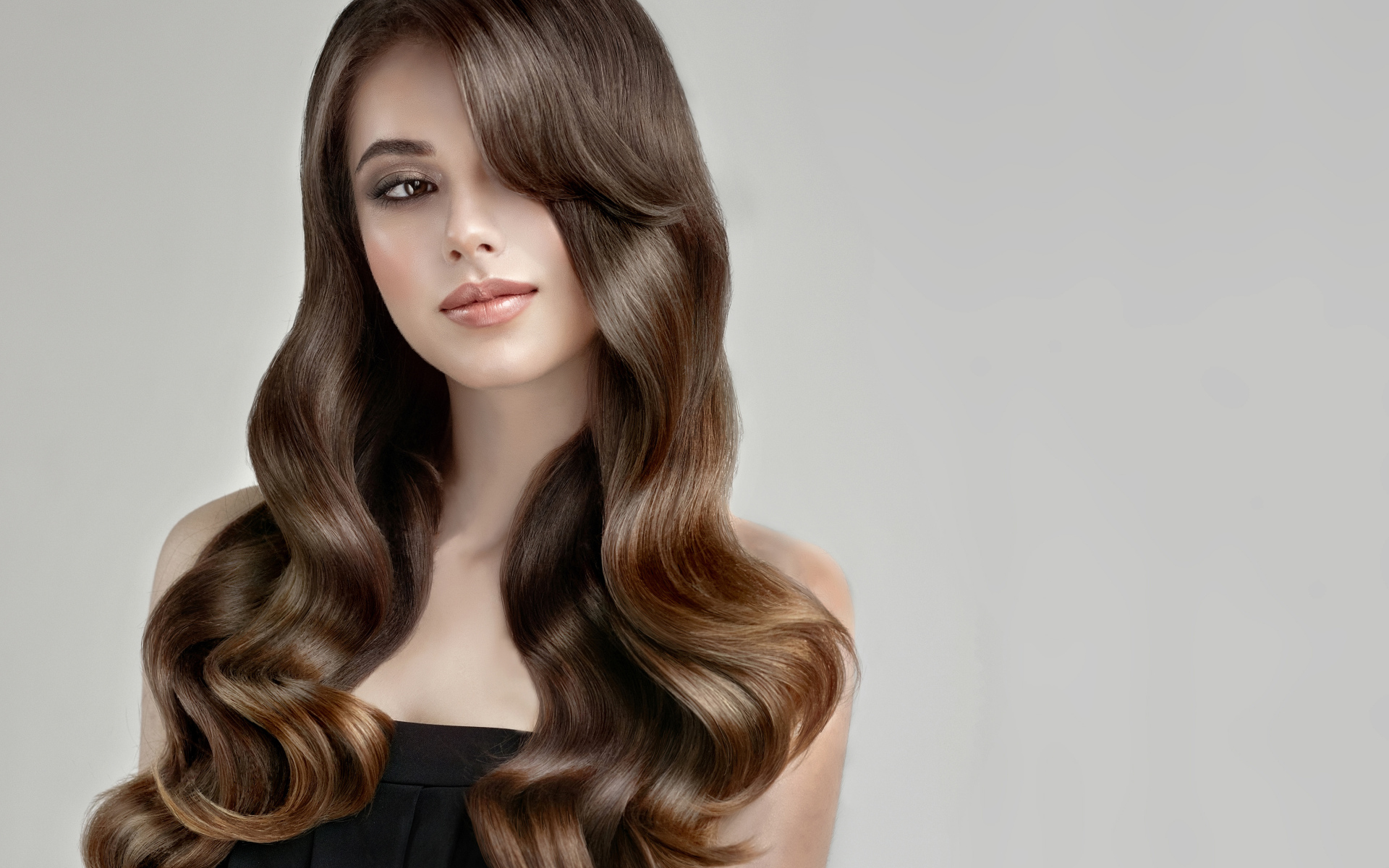Молодая девушка с красивыми длинными волосами на сером фоне