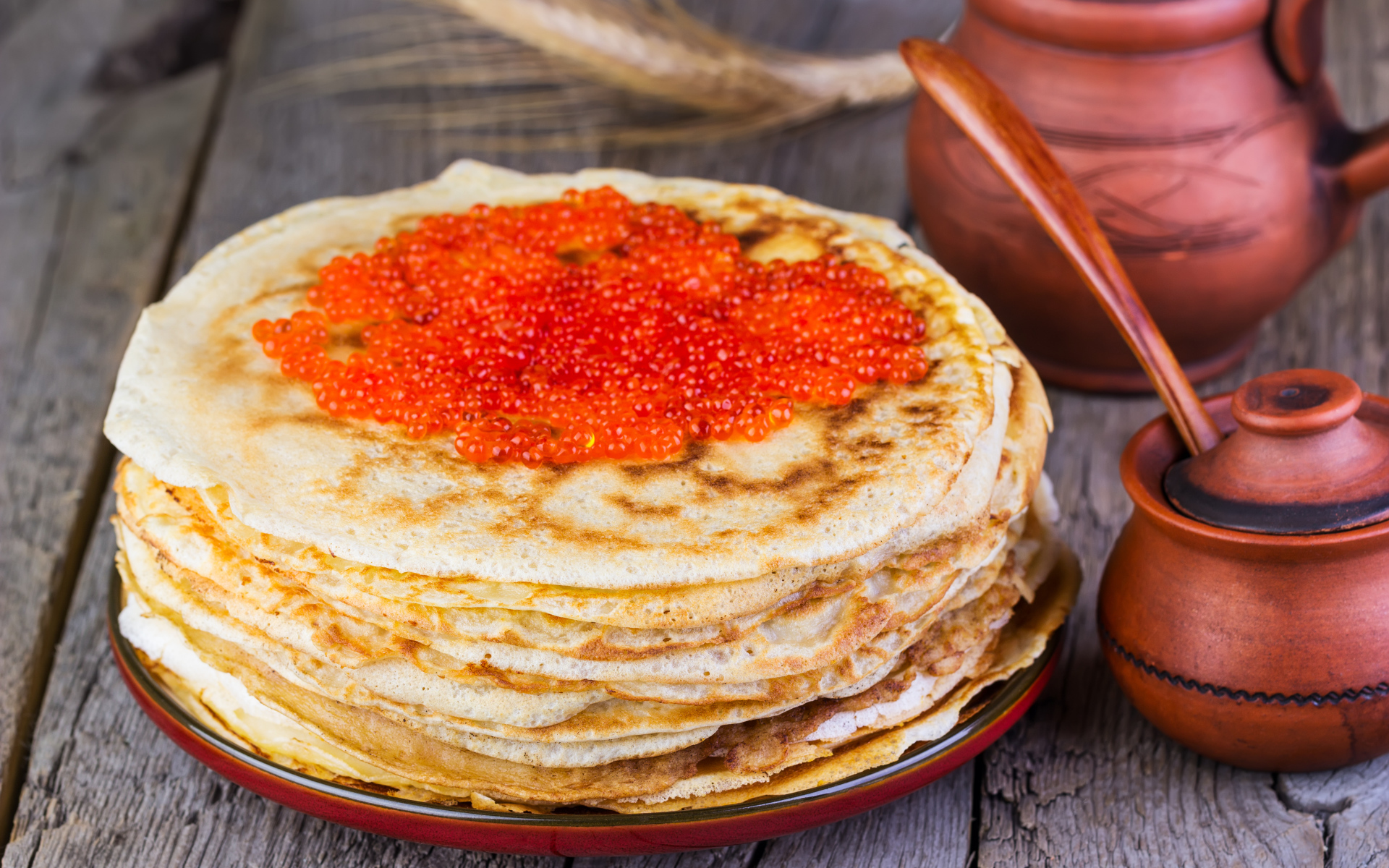 Стопка блинов с красной икрой на деревянном столе угощение на Масленицу