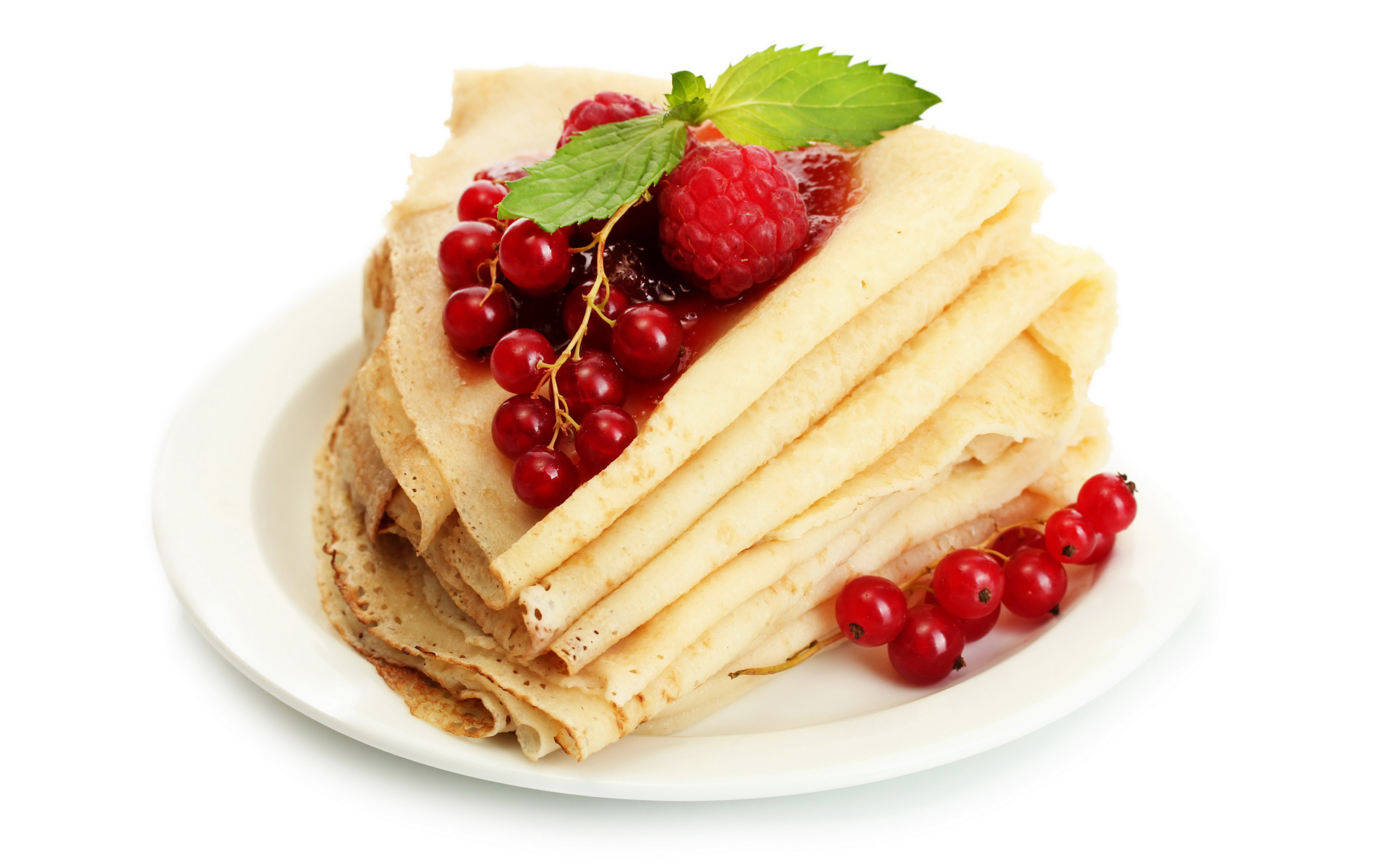 Тонкие блины с малиной и красной смородиной на белом фоне на Масленицу