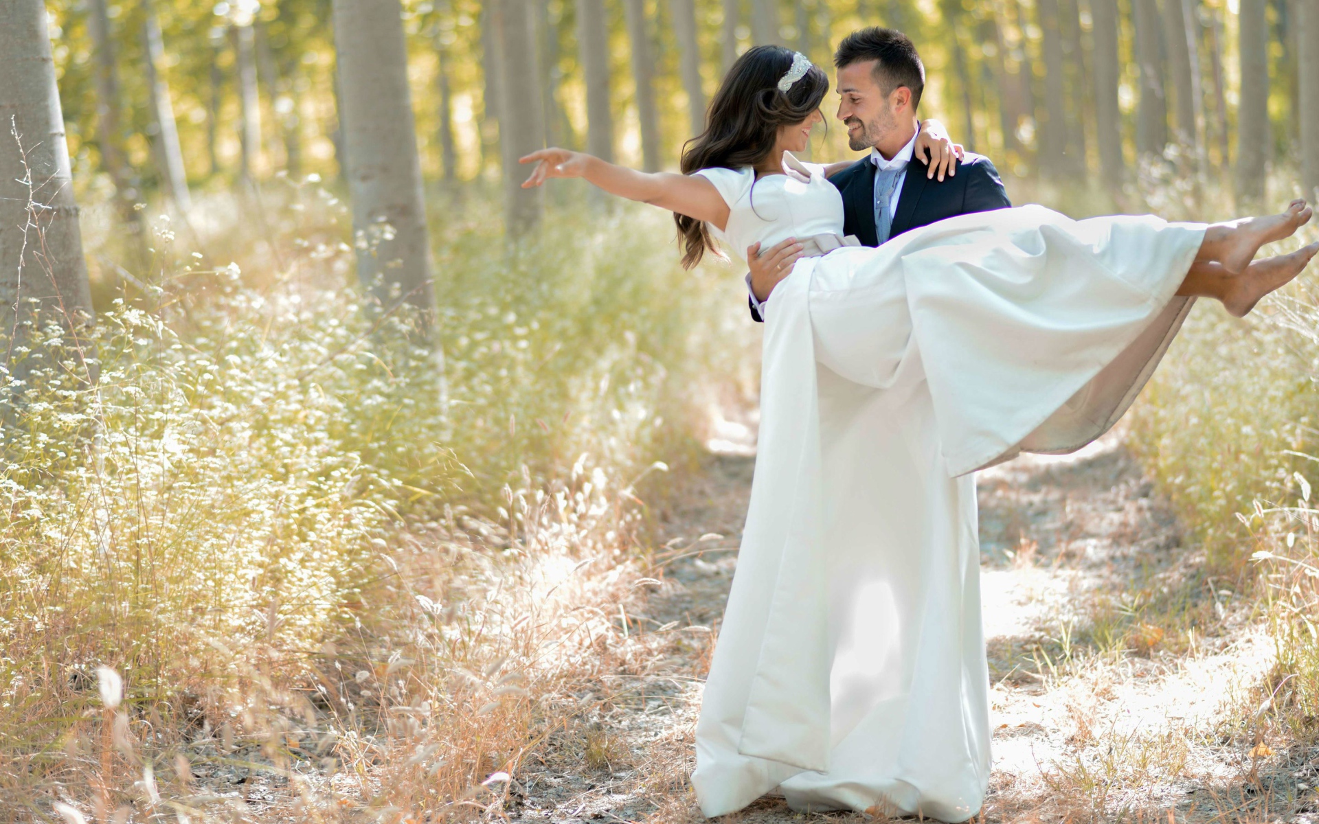 Парень жених держит на руках невесту в белом платье