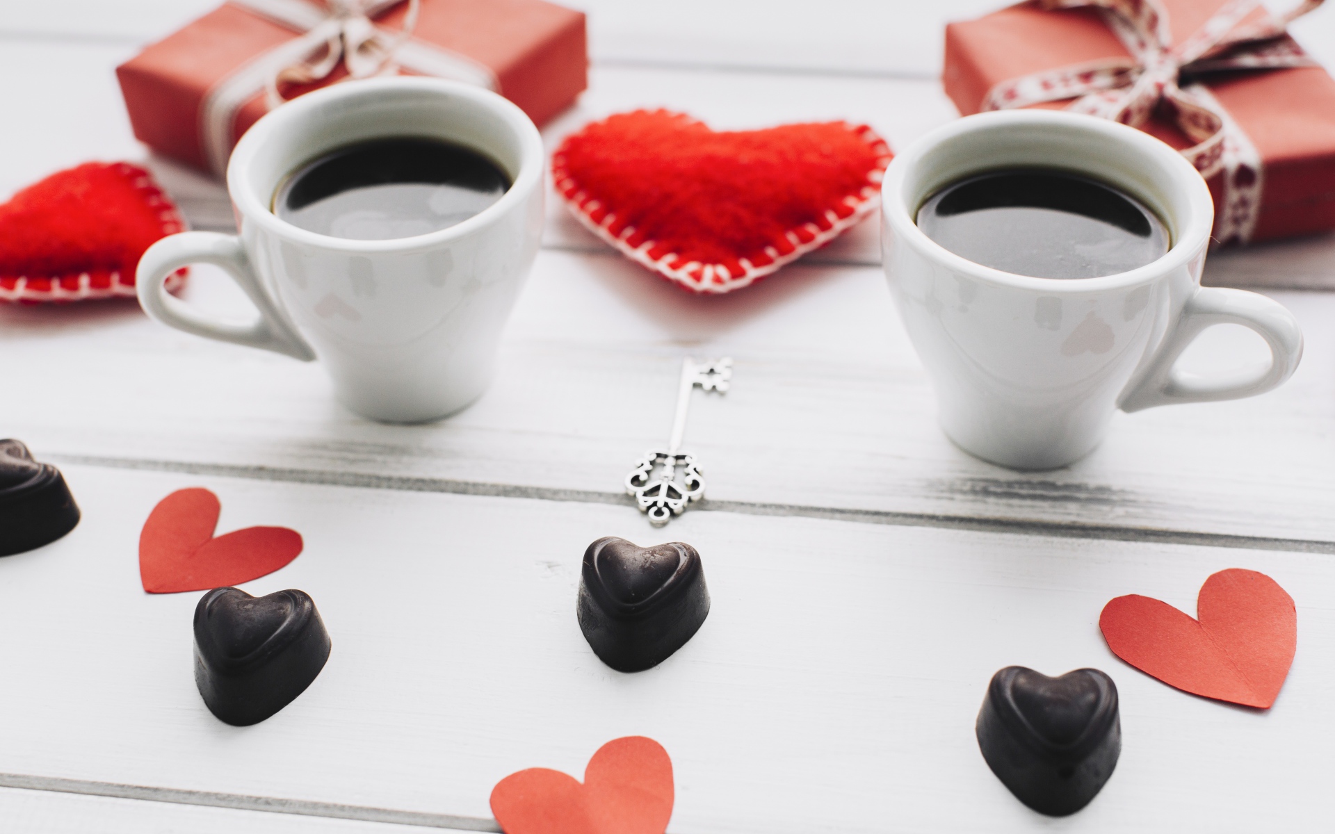 Две чашки кофе на столе с подарками, конфетами и сердечками