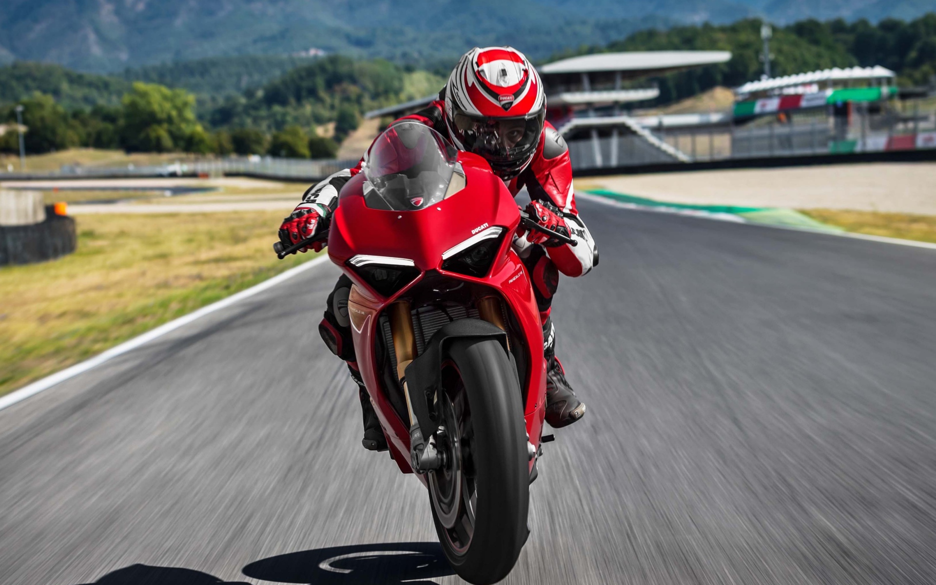 Красный мотоцикл  Ducati Panigale V4 S, 2018 на трассе с мотогонщиком