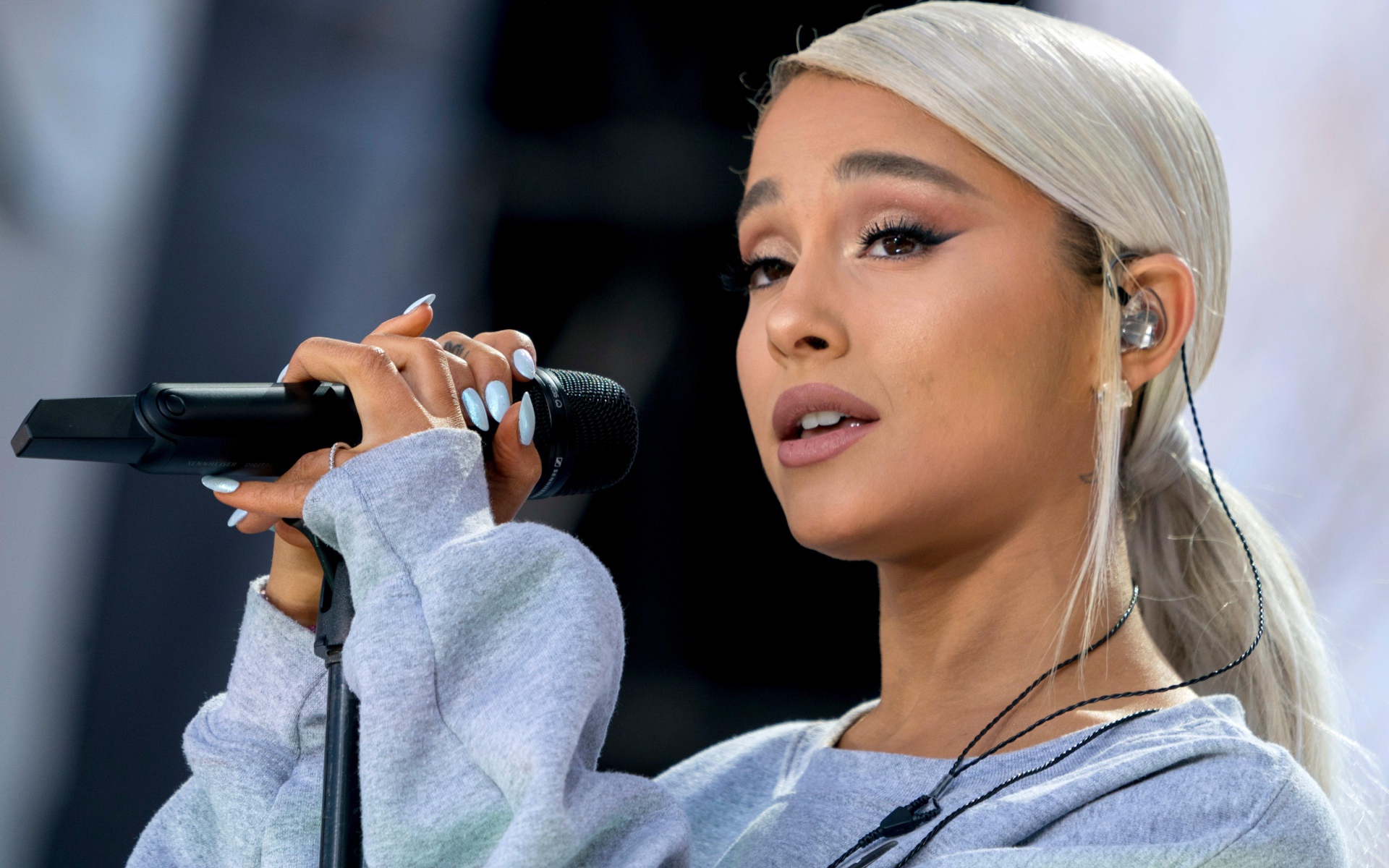 Светловолосая певица Ариана Гранде с микрофоном на сцене 