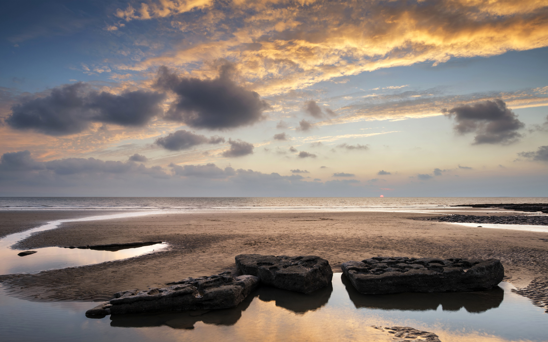Большие камни в воде на песке под красивым небом