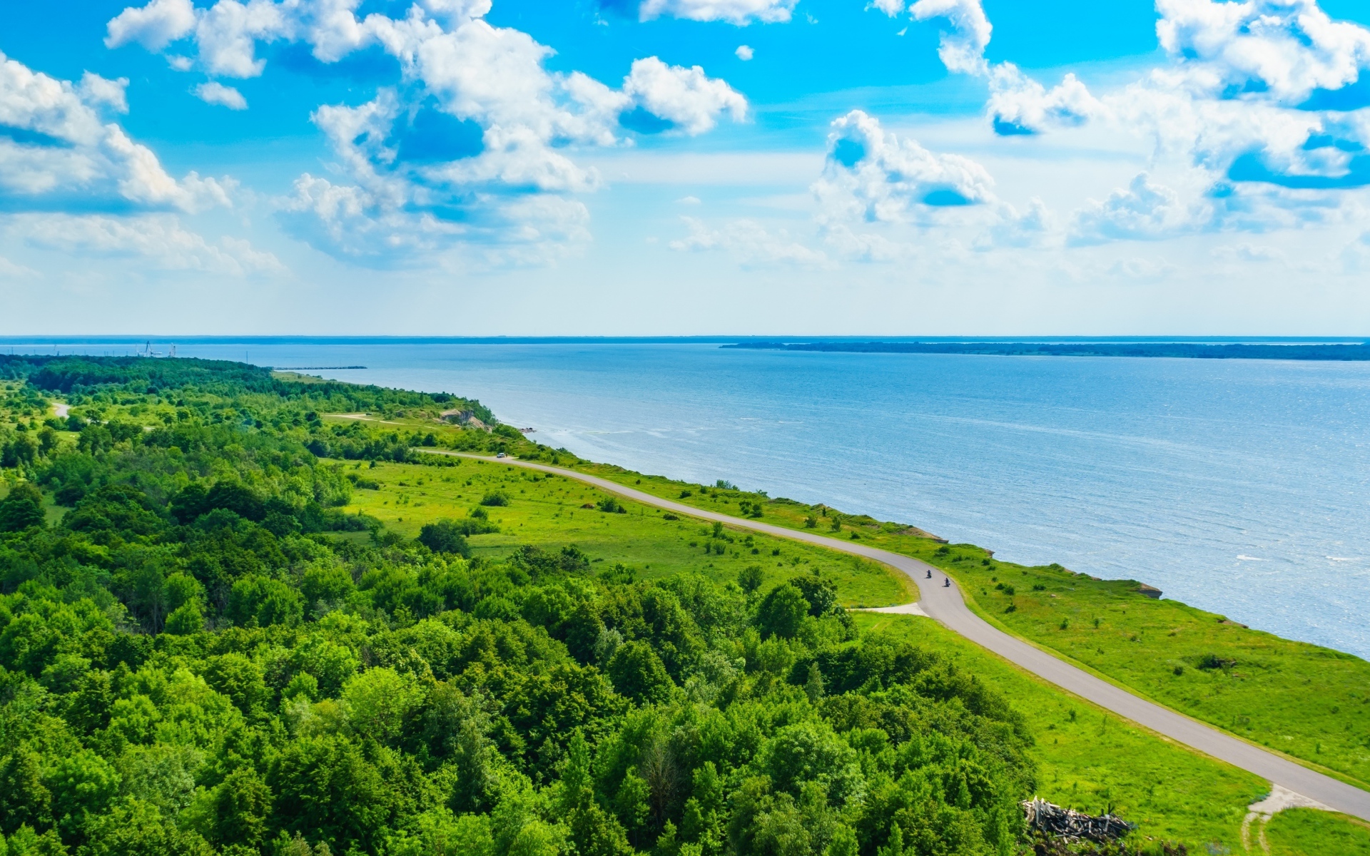 Дорога через побережье вдоль моря под голубым небом с белыми облаками