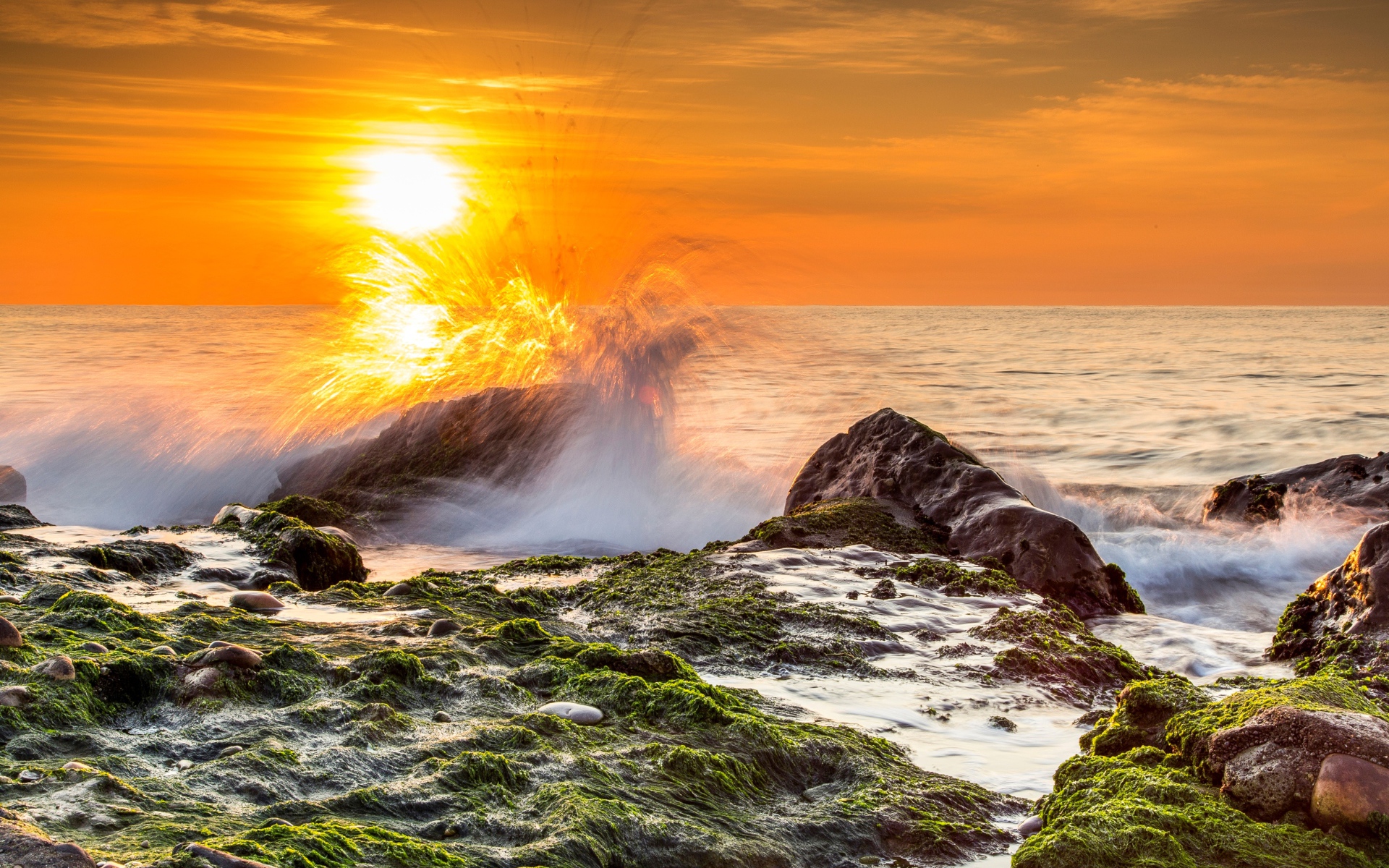 Бушующие волны в море бьются об камни на закате