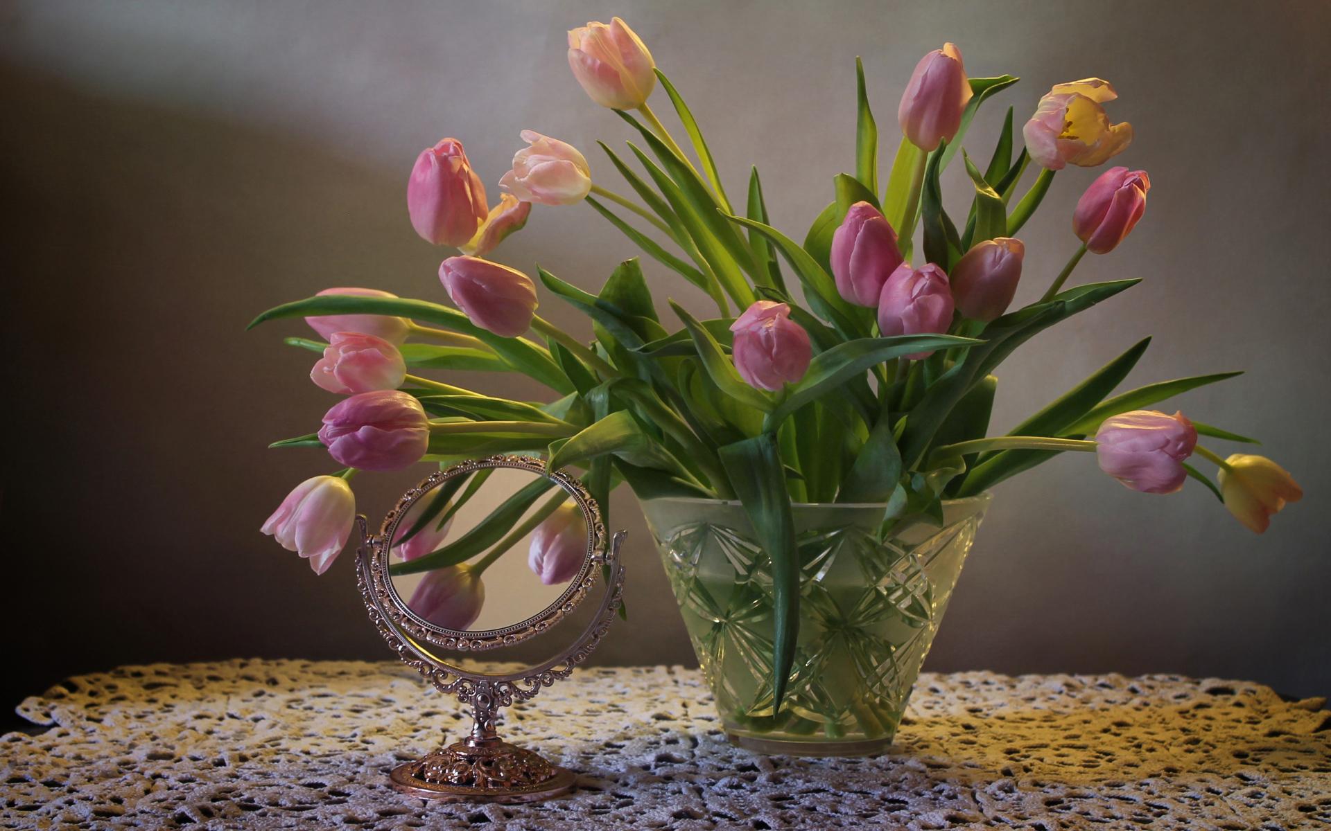 Розовые тюльпаны в стеклянной вазе на столе с зеркалом 