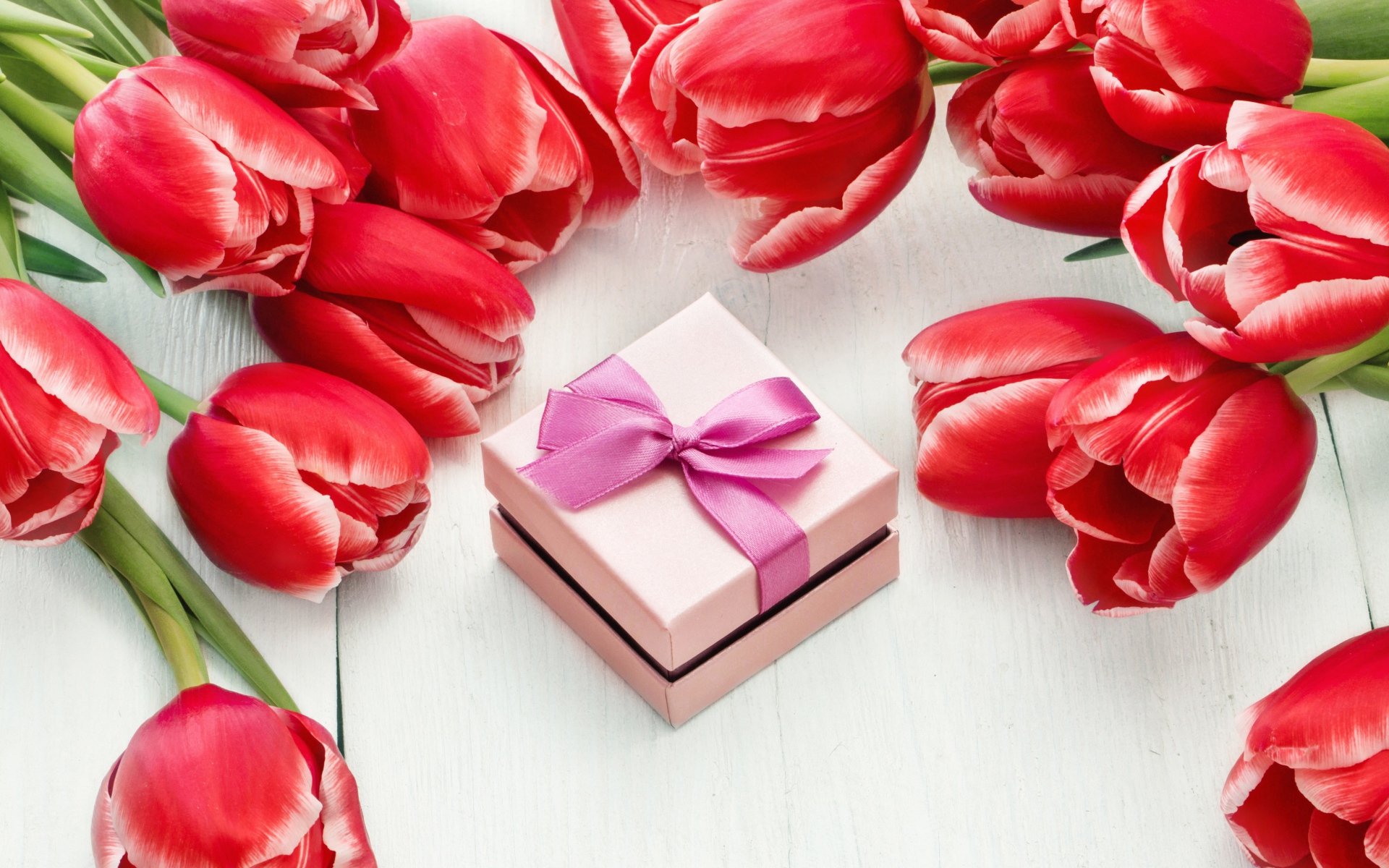 Красные тюльпаны на деревянной поверхности с подарком