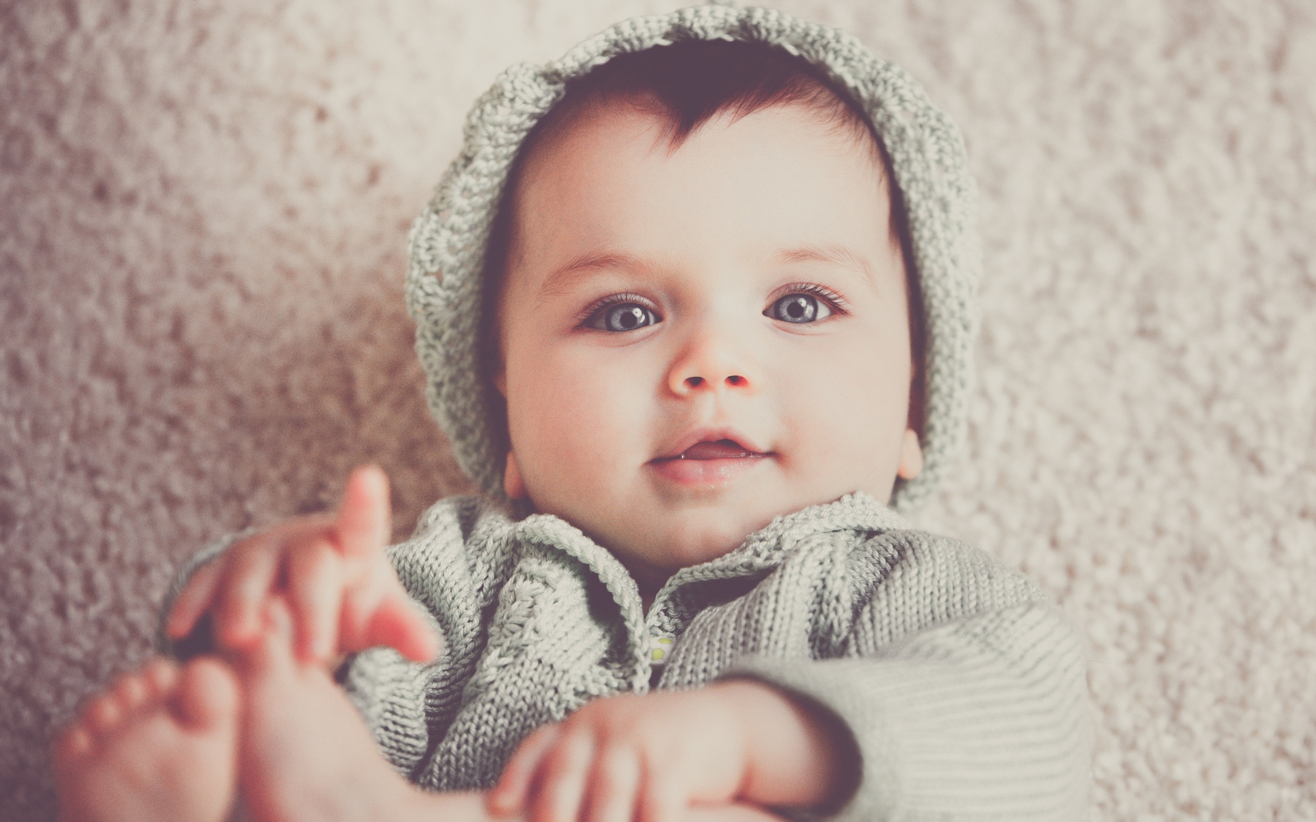 Маленький милый голубоглазый малыш в вязаном костюме