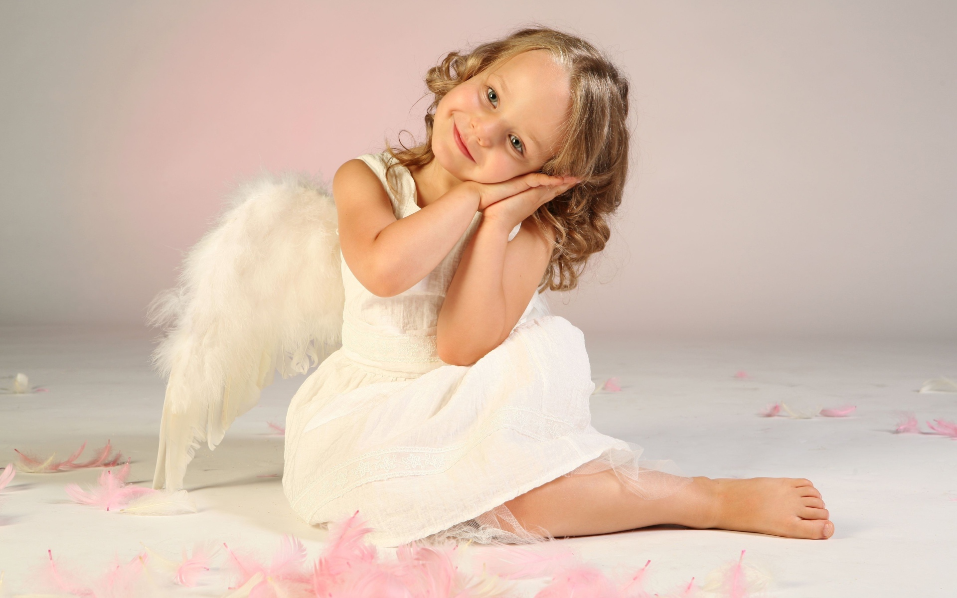 Милая маленькая девочка в белом платье с крыльями ангела