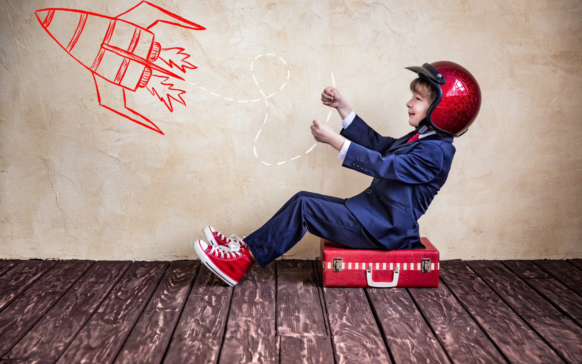 Маленький мальчик в шлеме сидит на чемодане