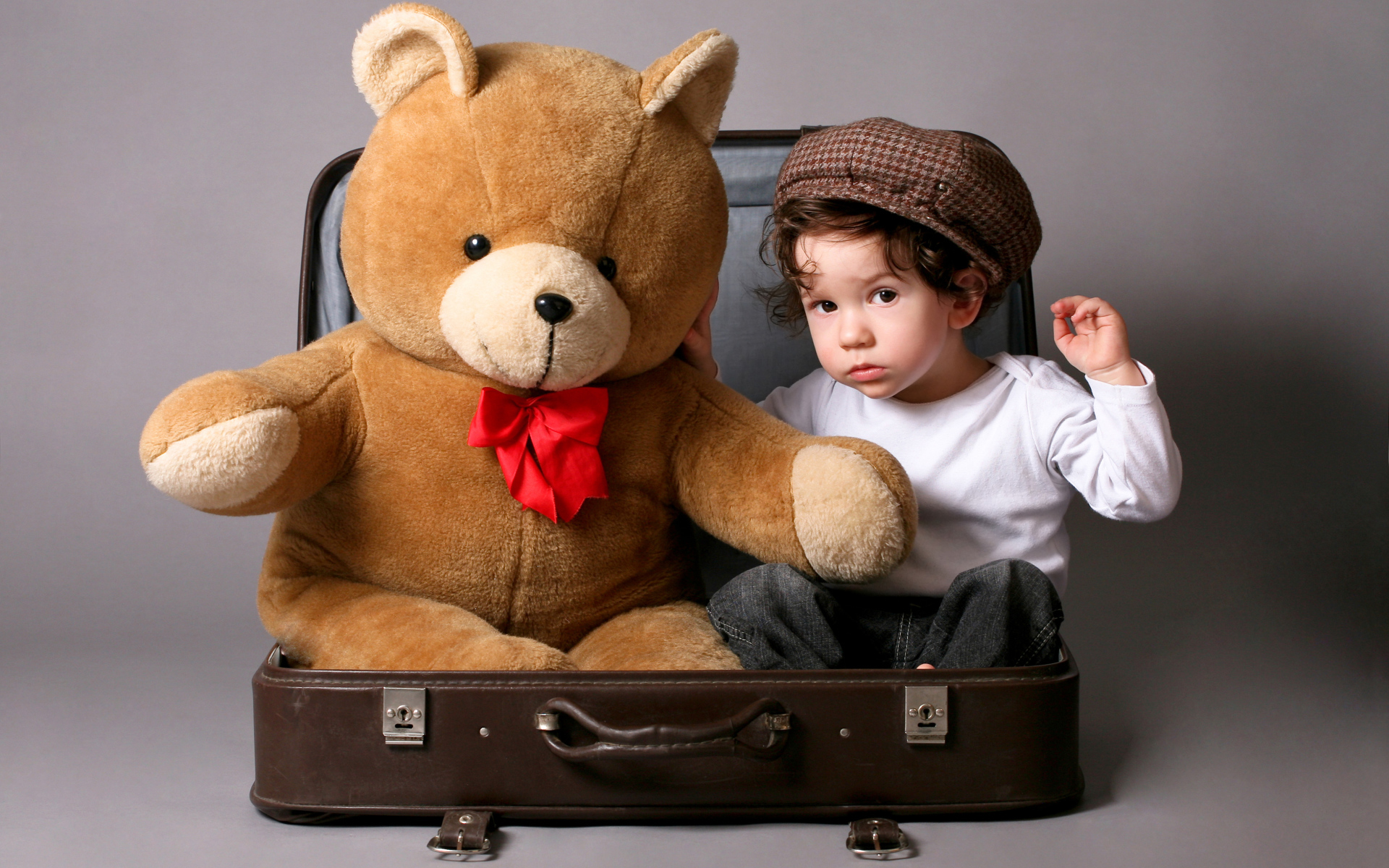 Маленький мальчик сидит в чемодане с плюшевым мишкой 