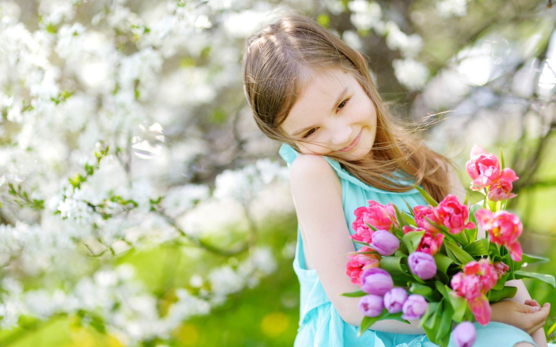 Красивая маленькая девочка с букетом тюльпанов весной