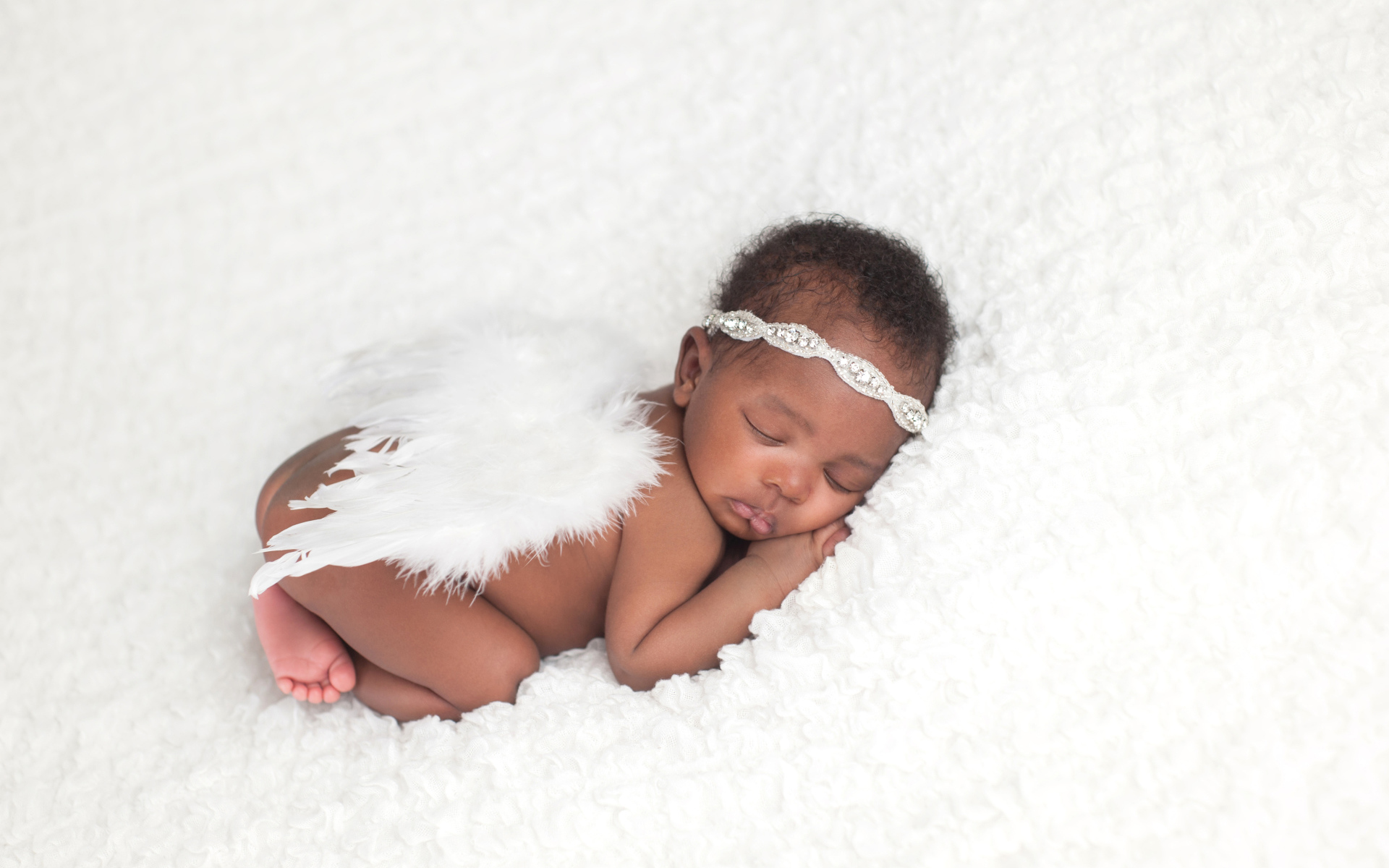 Темнокожий младенец спит с крыльями ангела