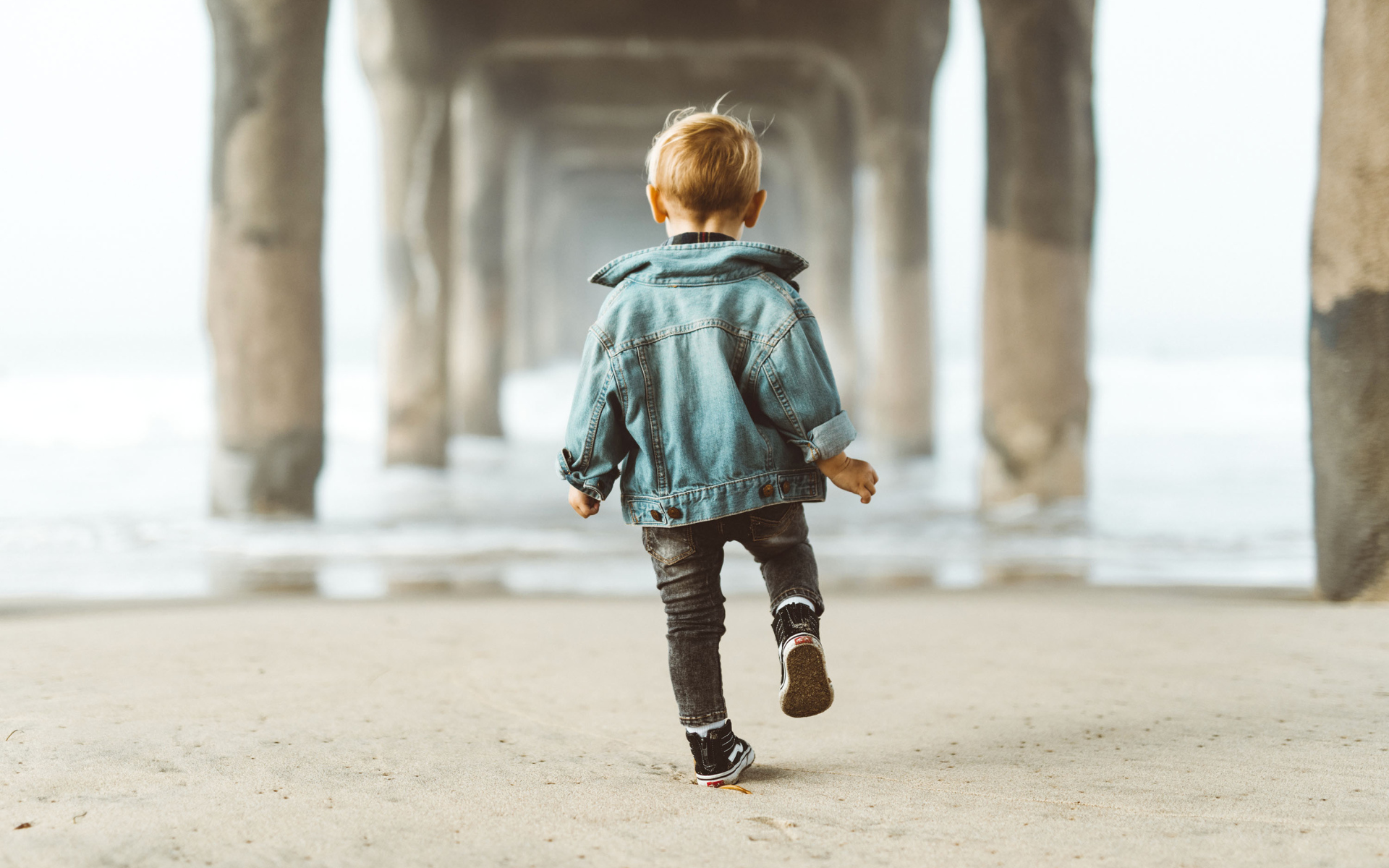 Маленький мальчик в джинсовой куртке спиной