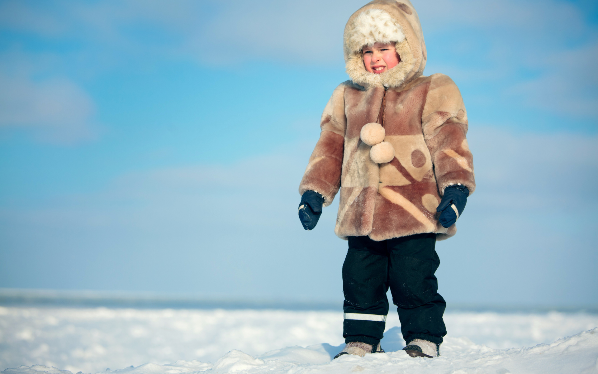 Маленький мальчик в теплой шубе на снегу 