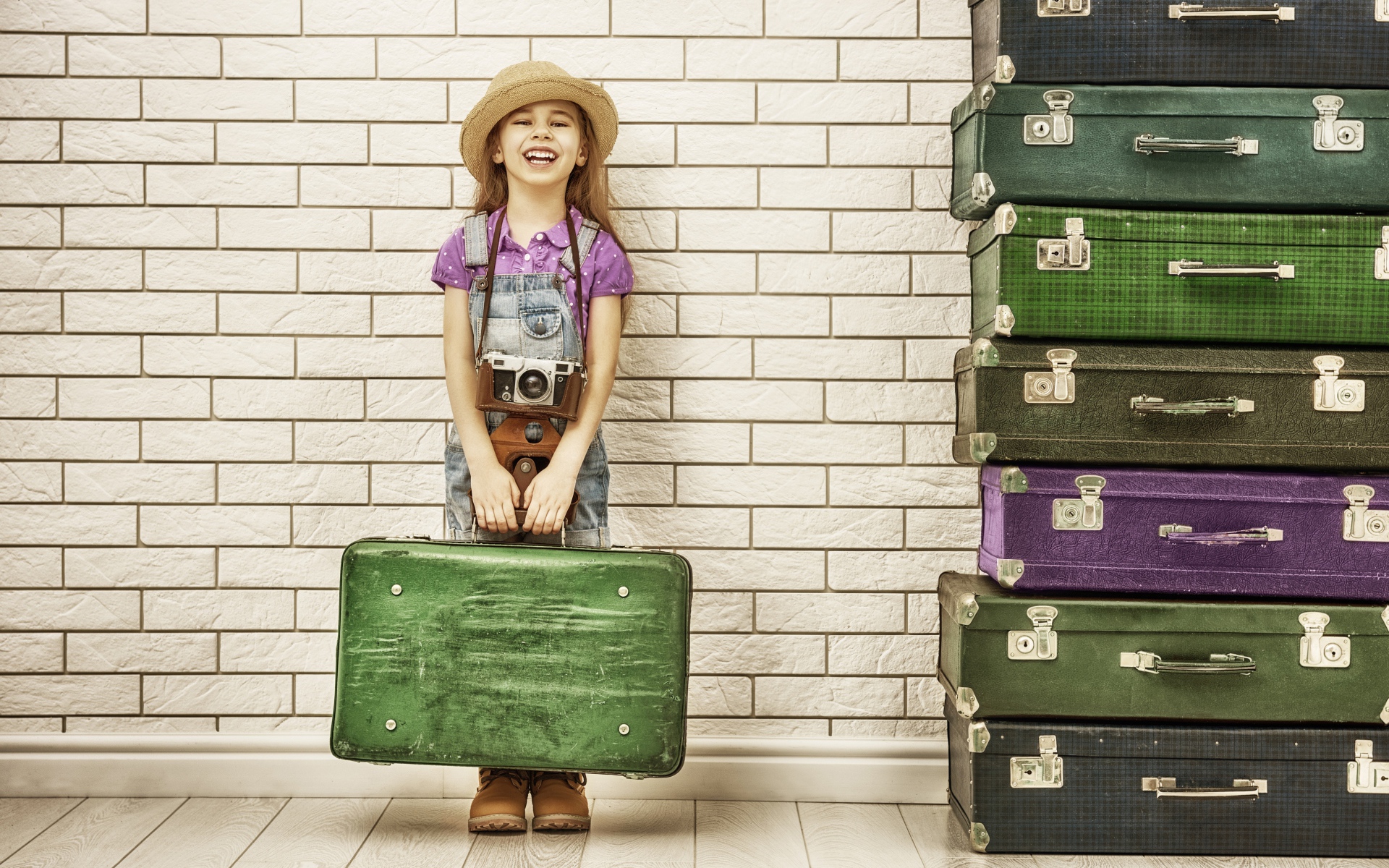 Маленькая девочка у стены с большими чемоданами