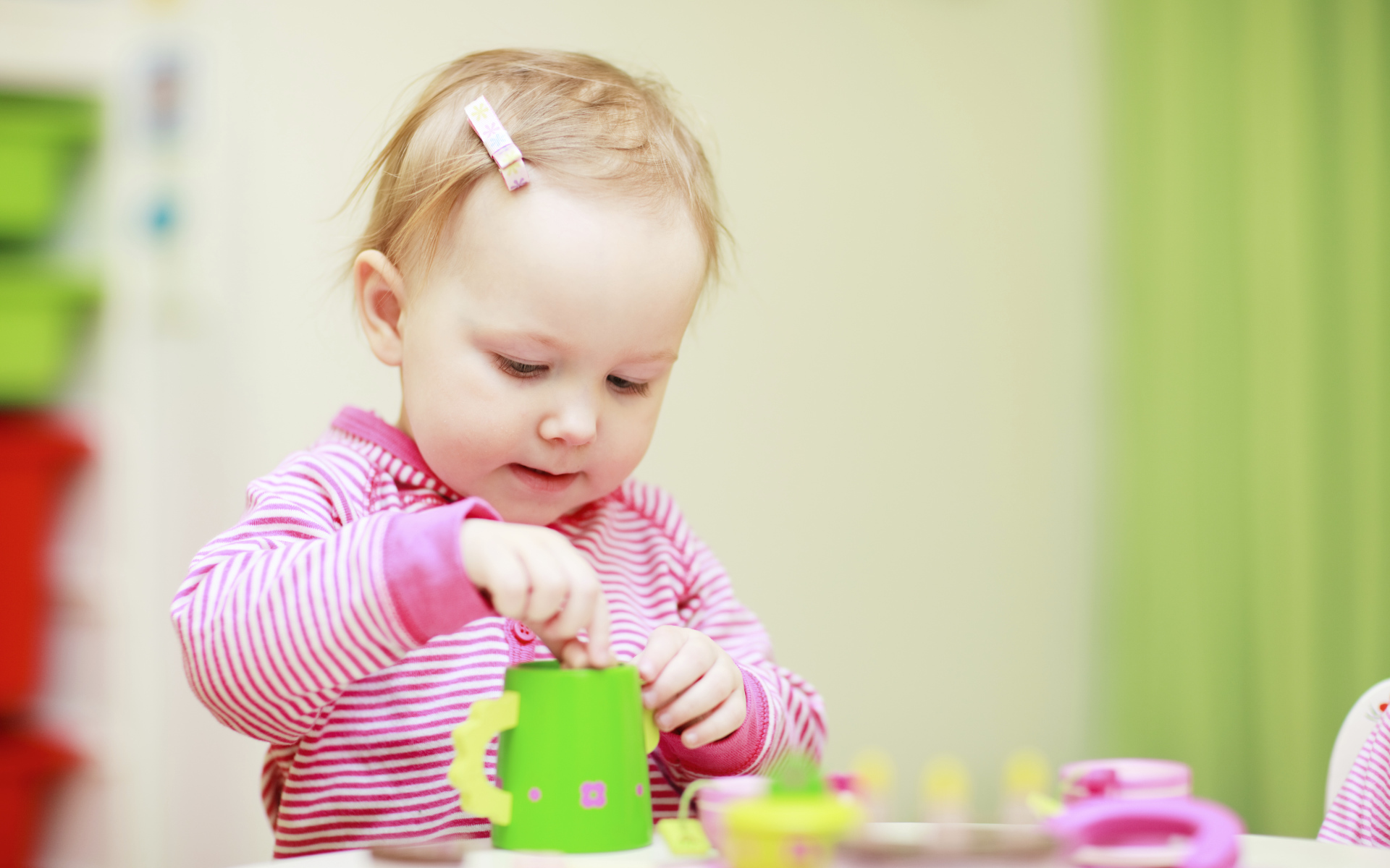 Маленькая девочка играет с посудой 