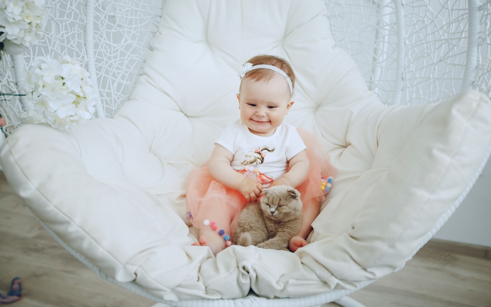 Маленький улыбающийся ребенок с котом сидит в белом кресле