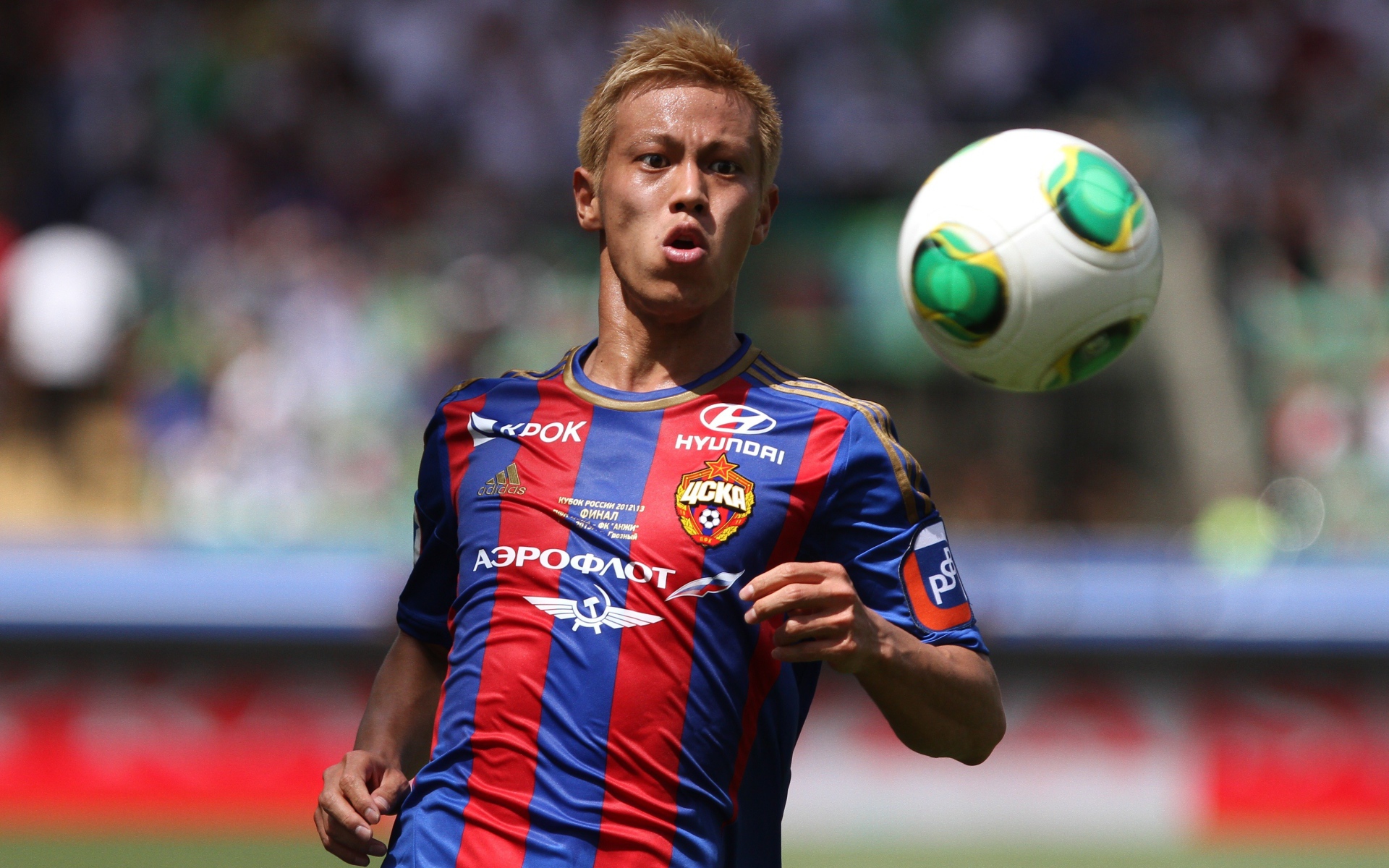 Японский футболист Кэйсукэ Хонда отбивает мяч на поле