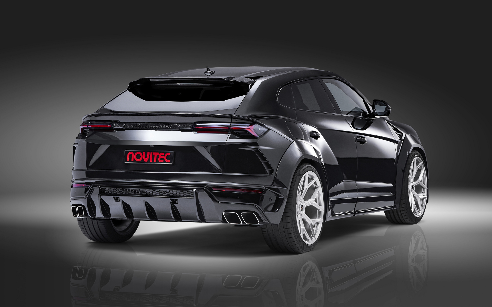 Черный Novitec Lamborghini Urus Esteso 2019 года вид сзади на сером фоне