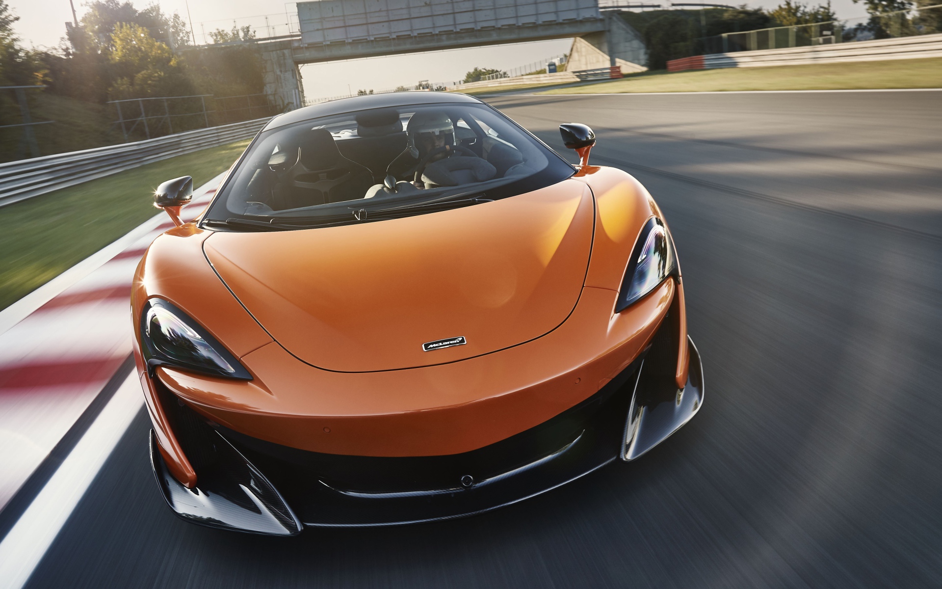 Спортивный оранжевый автомобиль McLaren 600LT 2019 года на трассе