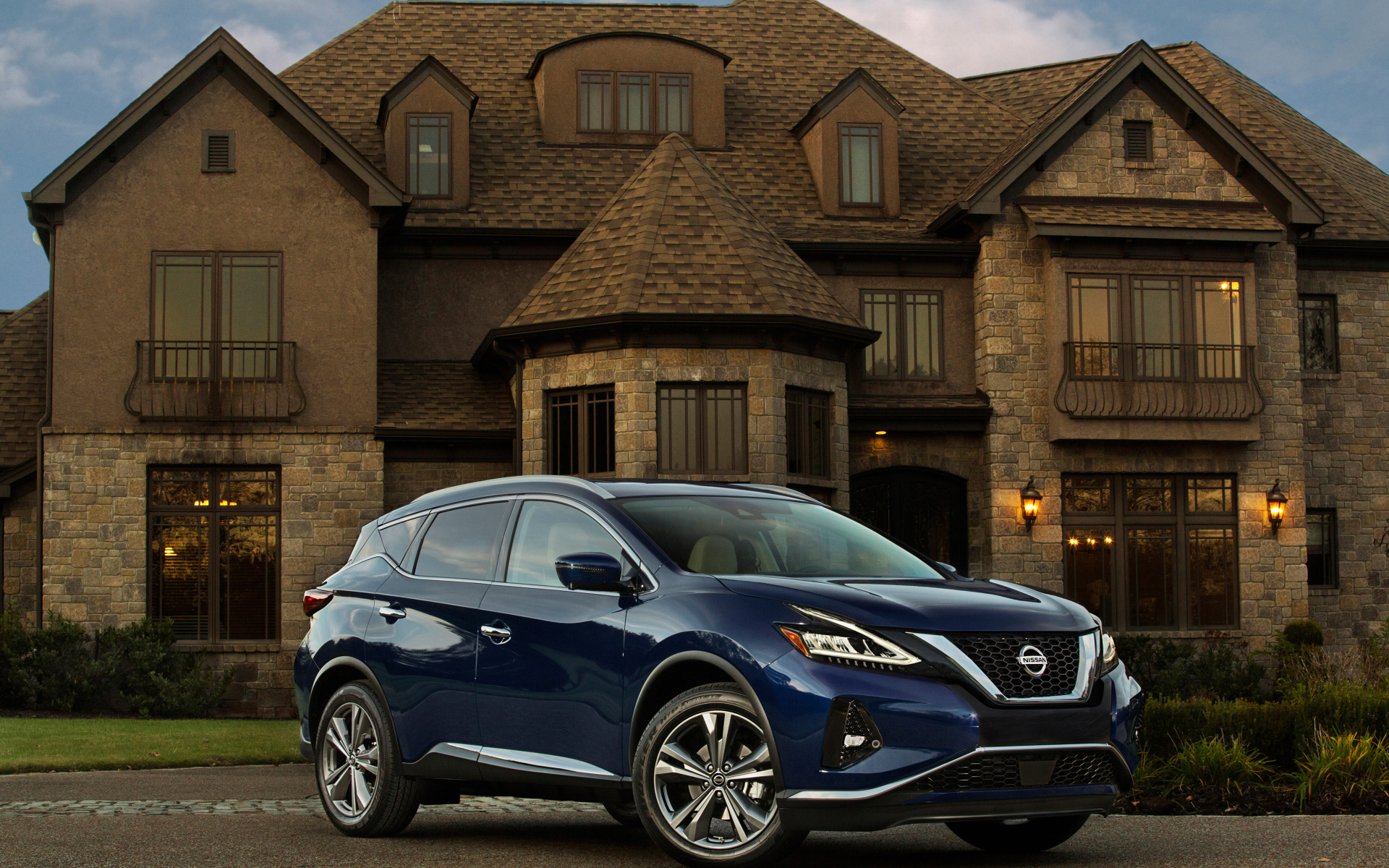 Синий автомобиль Nissan Murano на фоне особняка