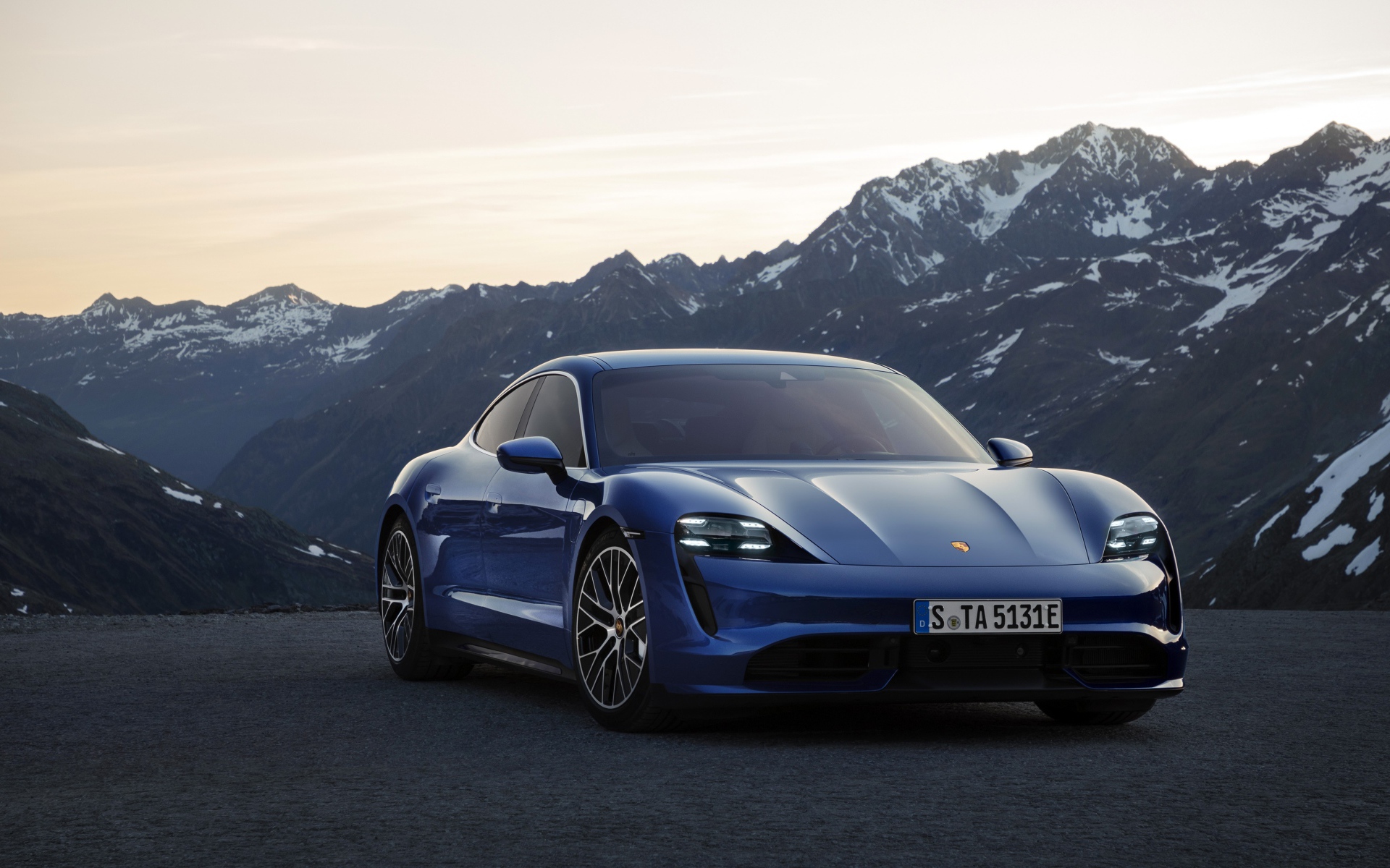 Синий стильный автомобиль Porsche Taycan Turbo 2019 года на фоне гор