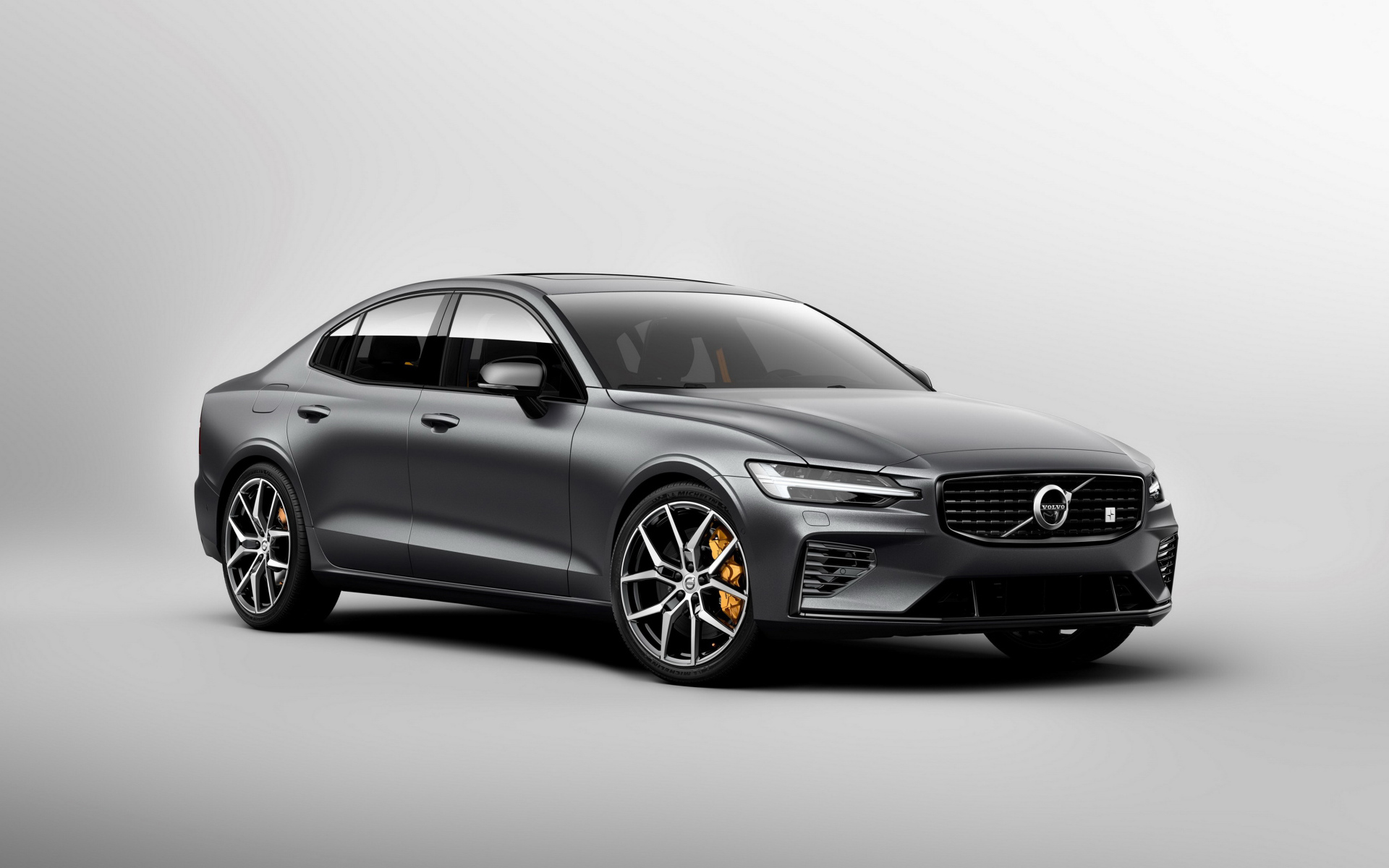 Серебристый автомобиль Volvo S60, 2018 года на сером фоне