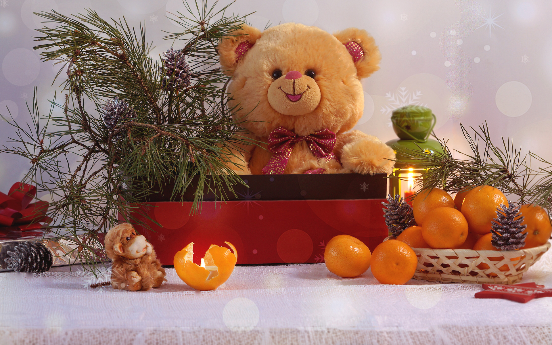 Медвежонок Тедди в коробке с еловой веткой на столе с мандаринами 