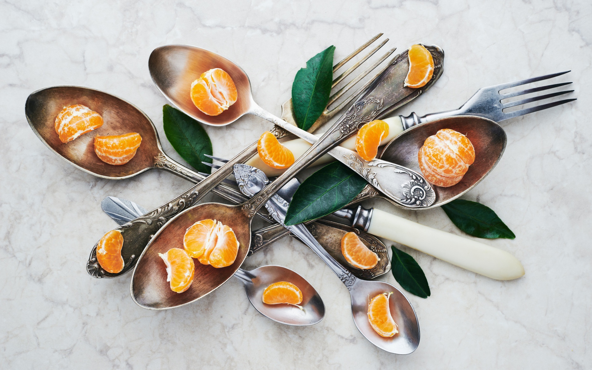 Столовые приборы на столе с дольками мандарина