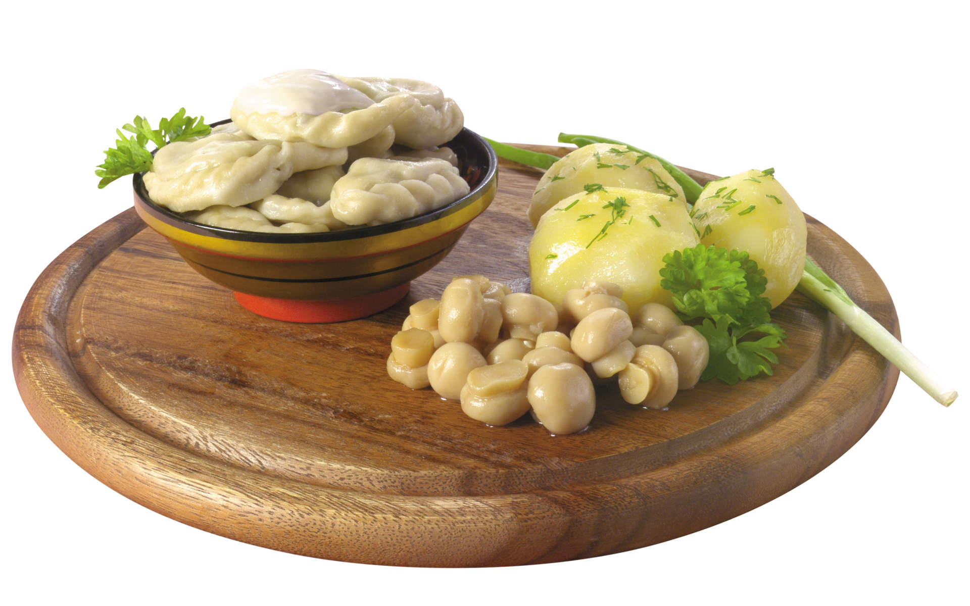 Вареники с грибами и вареной картошкой на деревянной доске на белом фоне