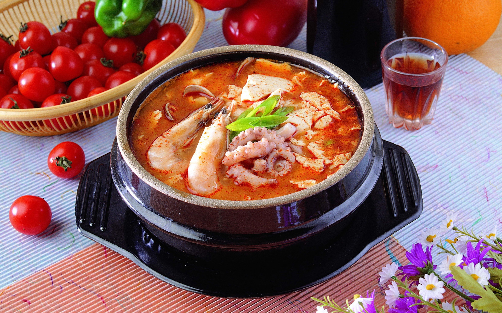 Тарелка красного супа с морепродуктами на столе с овощами 