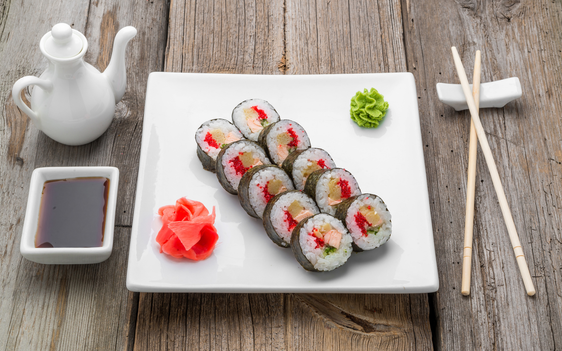 Суши на большой белой тарелке с соусом васаби и имбирем на столе соевым соусом