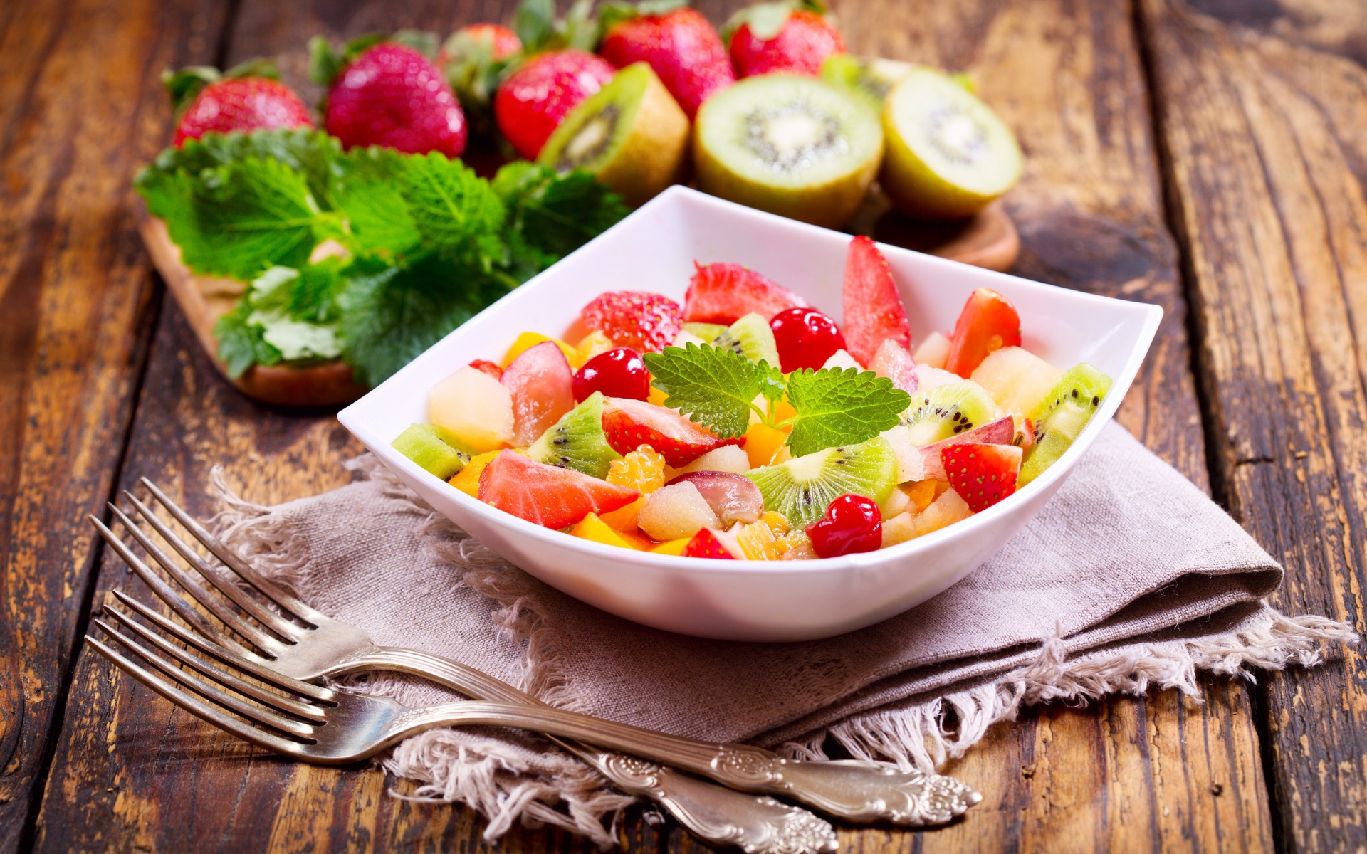 Фруктовый салат в миске на столе с вилками