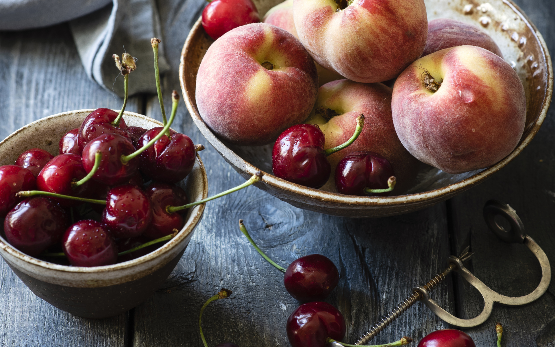 Спелые персики в миске на столе с черешней