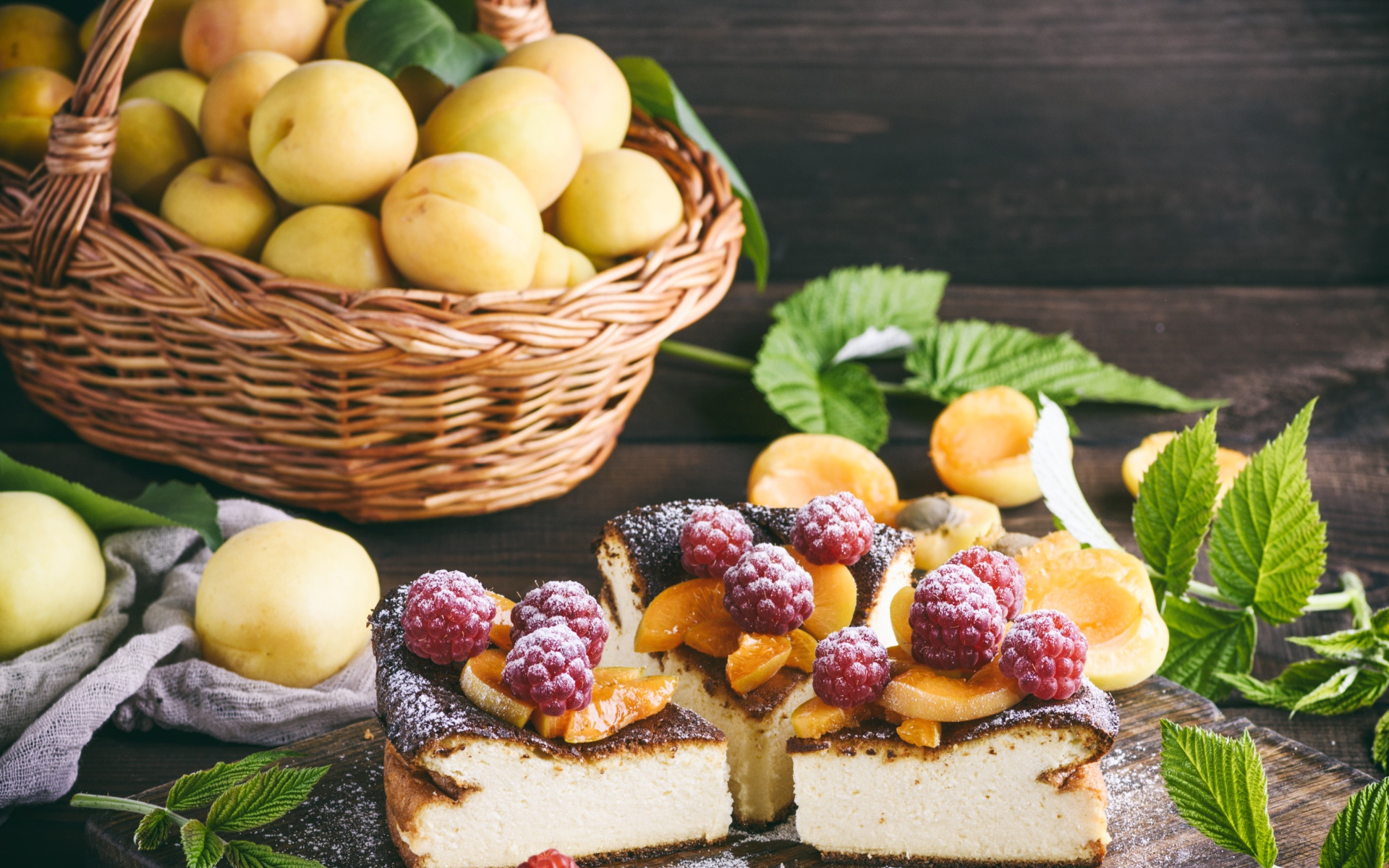Вкусный фруктово - ягодный пирог на столе с корзиной с абрикосами