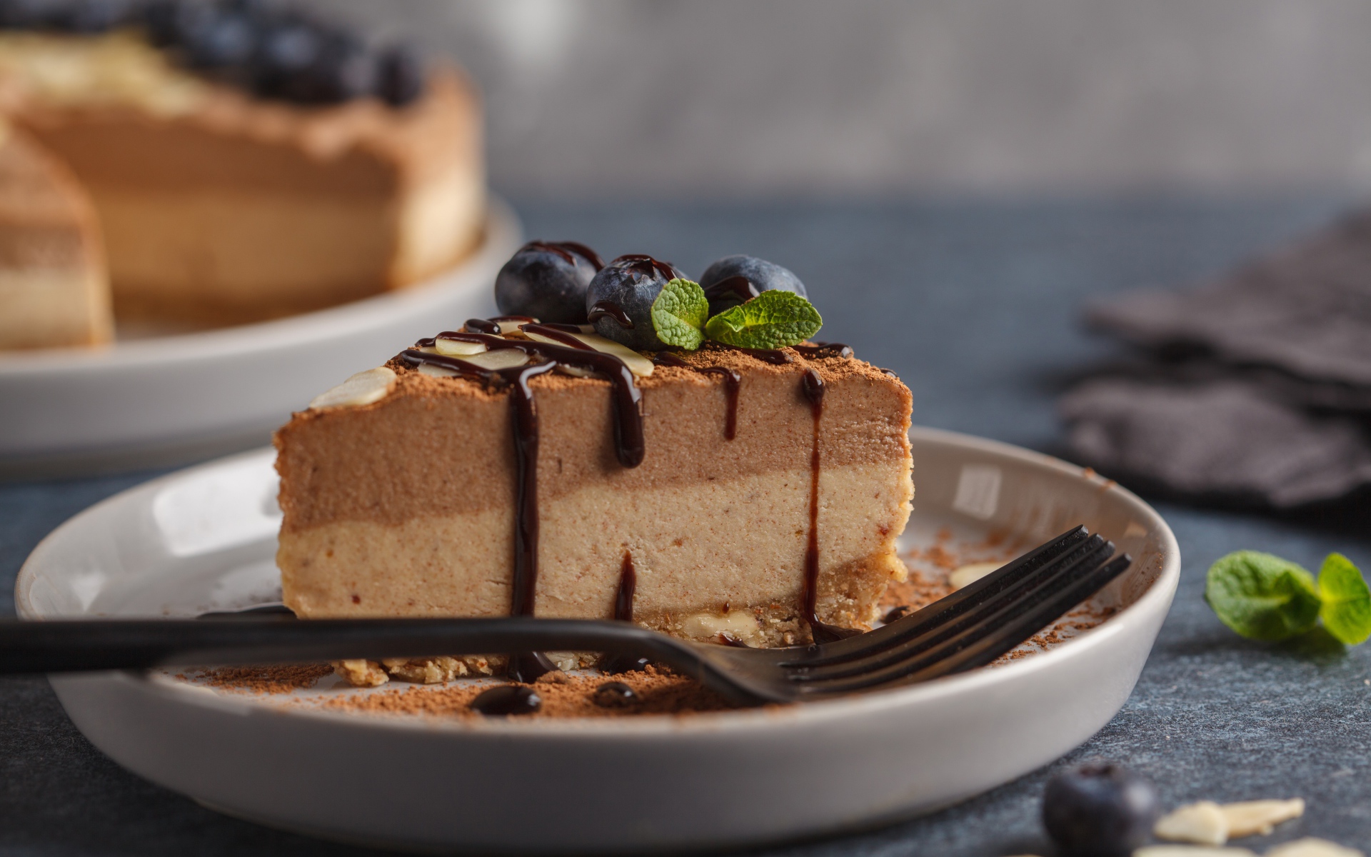 Кусок чизкейка с черникой и шоколадом на тарелке с вилкой