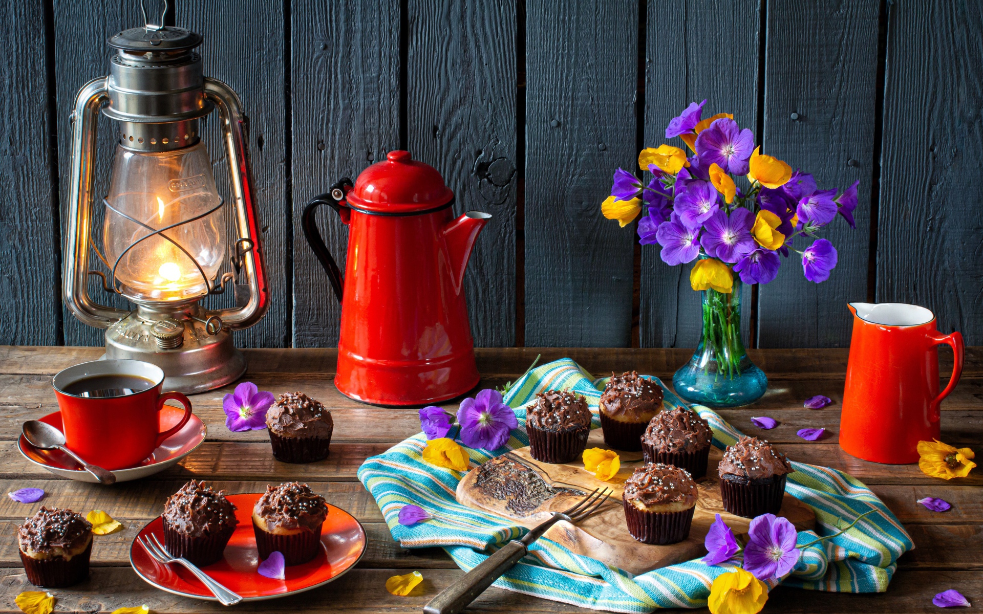 Аппетитные свежие кексы с кремом на столе с кофе, лампой и букетом цветов