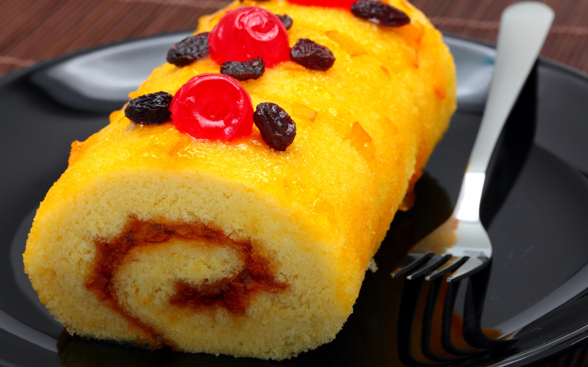 Бисквитный рулет с сухофруктами на тарелке с вилкой