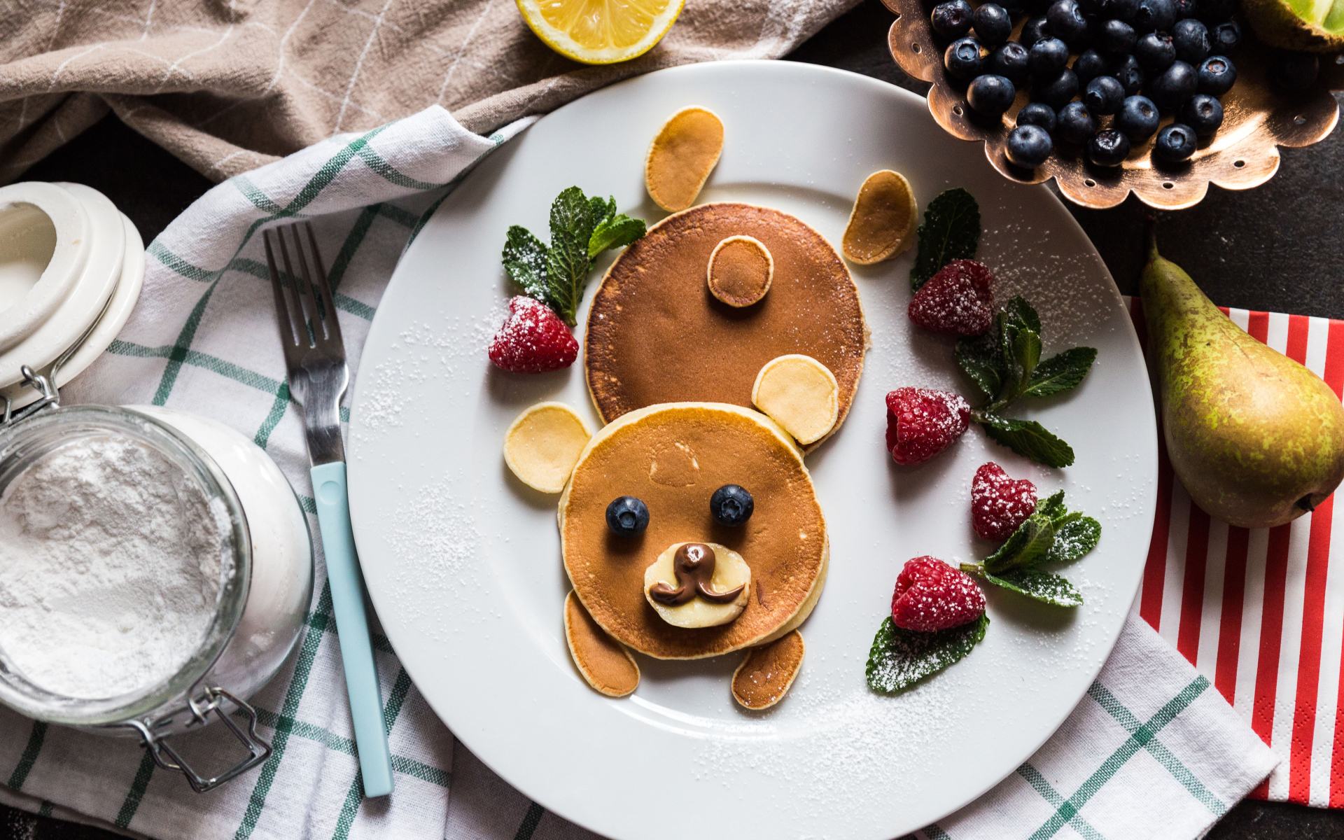 Медведь из оладьев на тарелке с малиной и сахарной пудрой