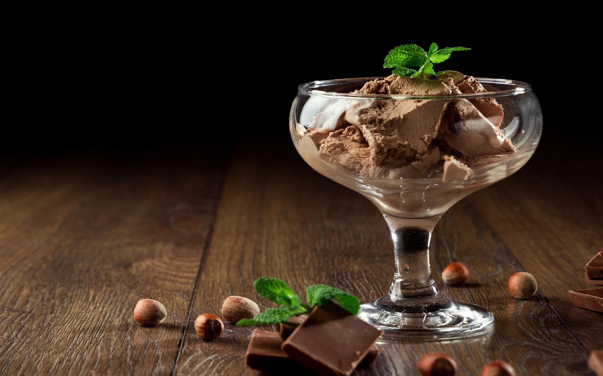 Кофейное мороженое в креманке на столе с шоколадом и орехами