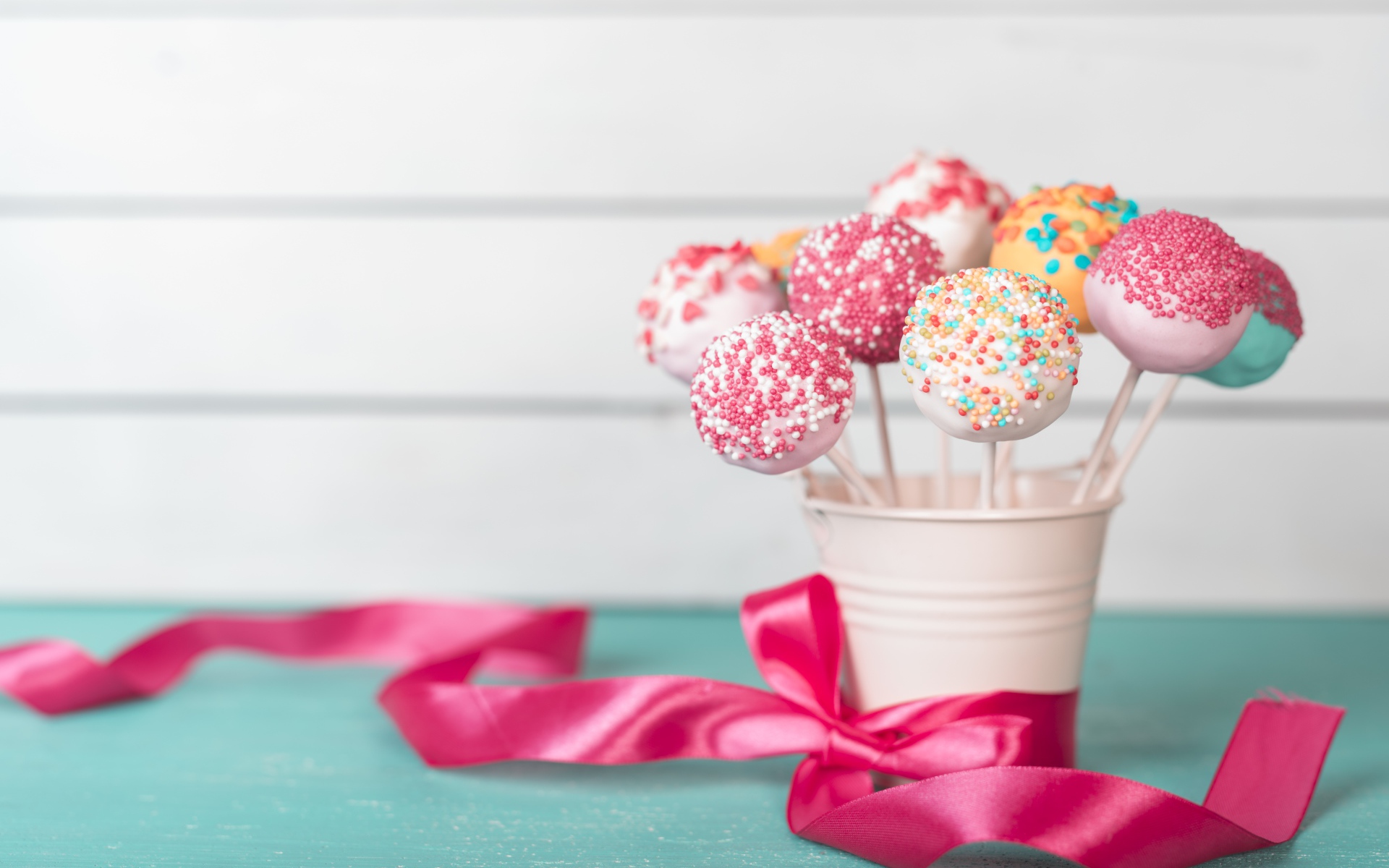Леденцы в стакане на столе с розовым бантом из ленты