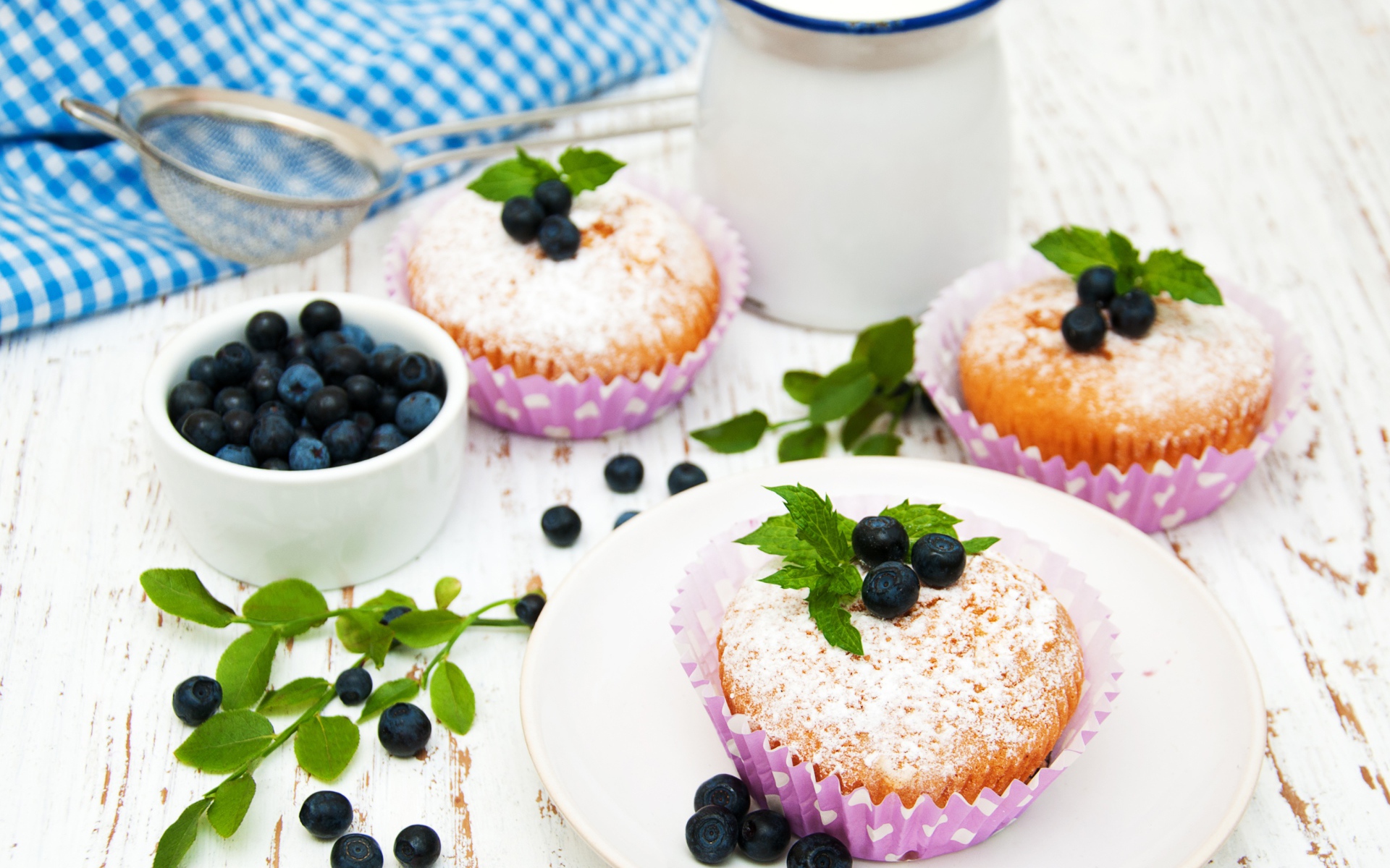 Кексы с сахарной пудрой на столе с молоком и черникой
