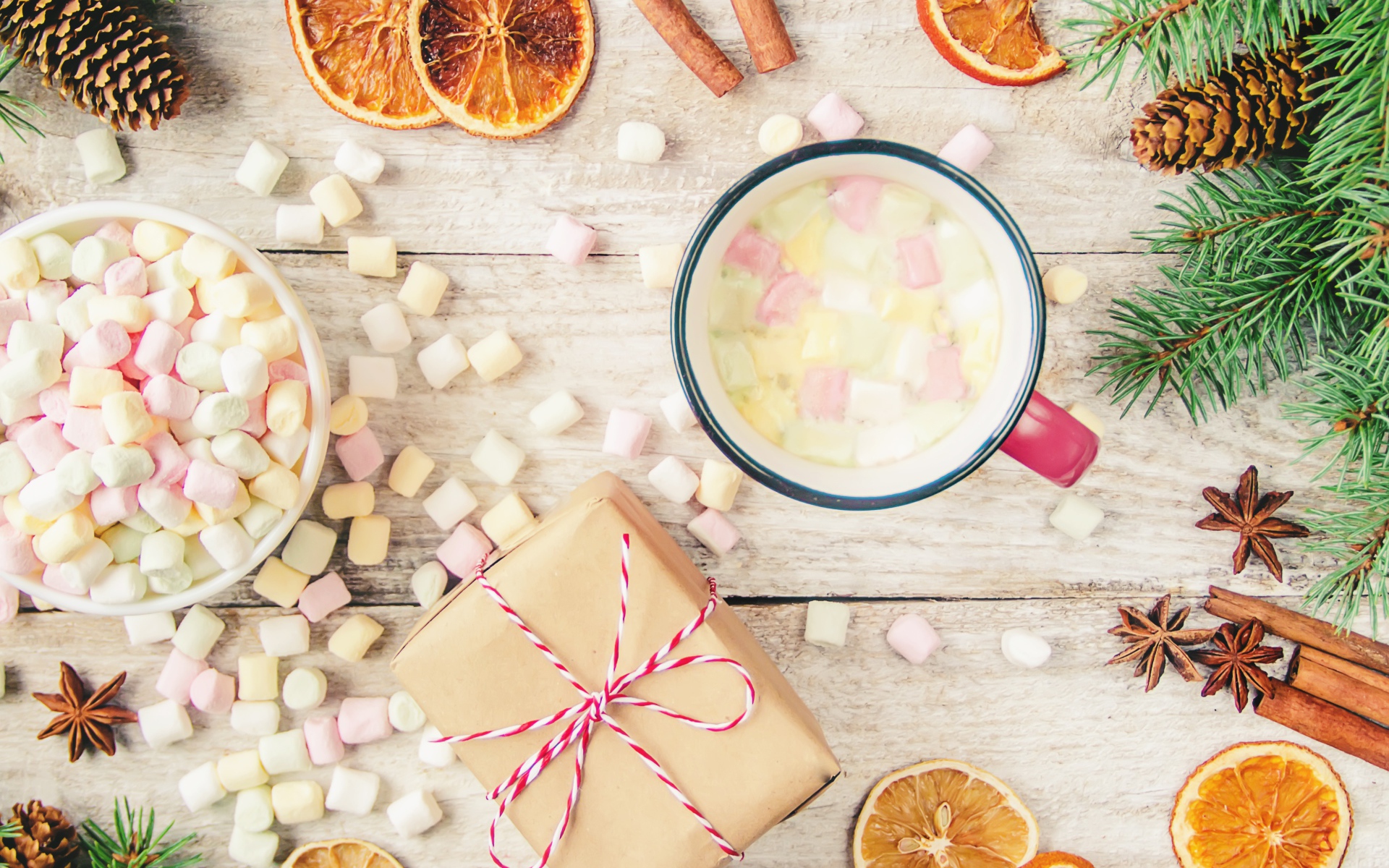 Кружка горячего напитка на столе с маршмеллоу, пряностями и подарком