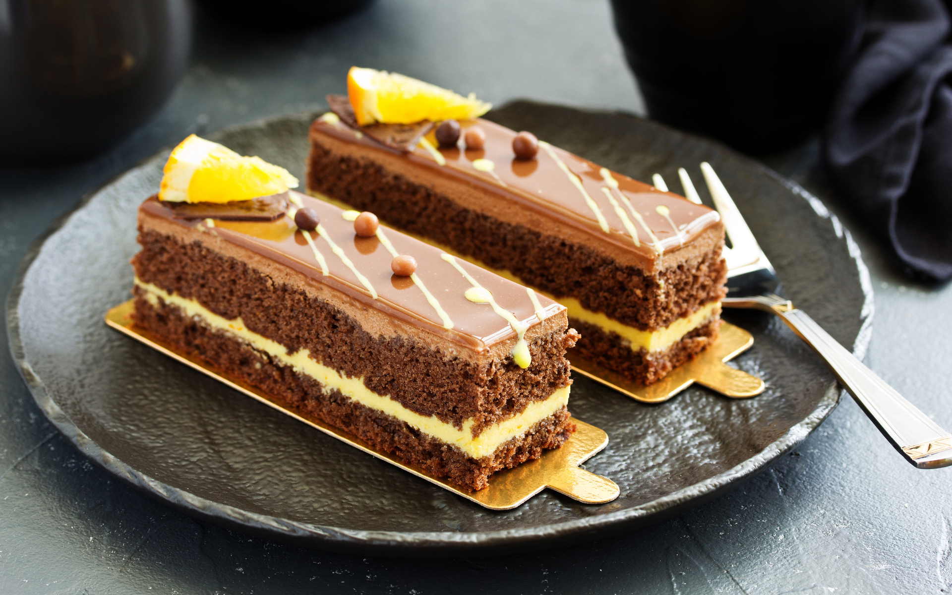 Два вкусных шоколадных пирожный на большой тарелке с вилкой