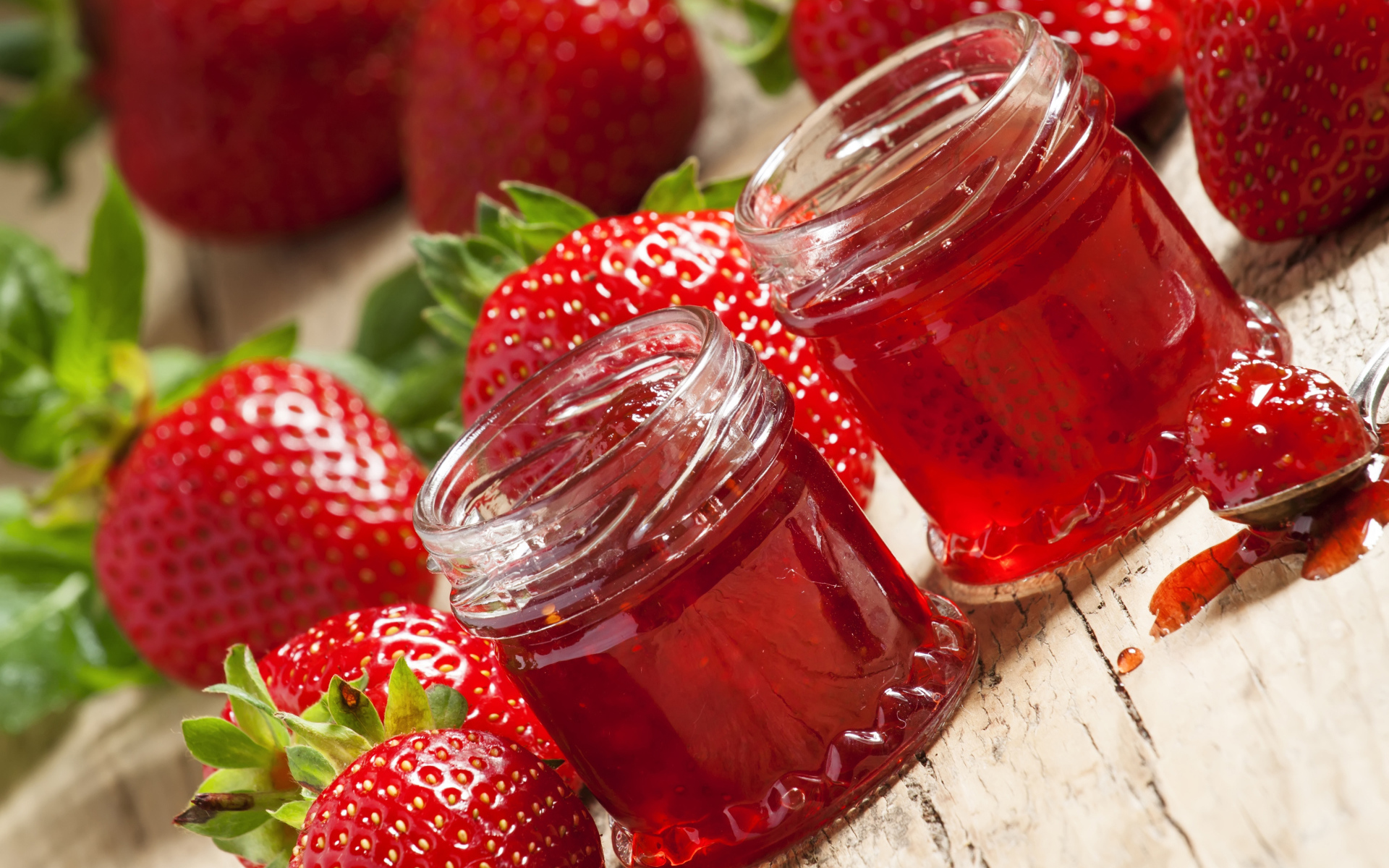 Две баночки клубничного джема на столе с клубникой