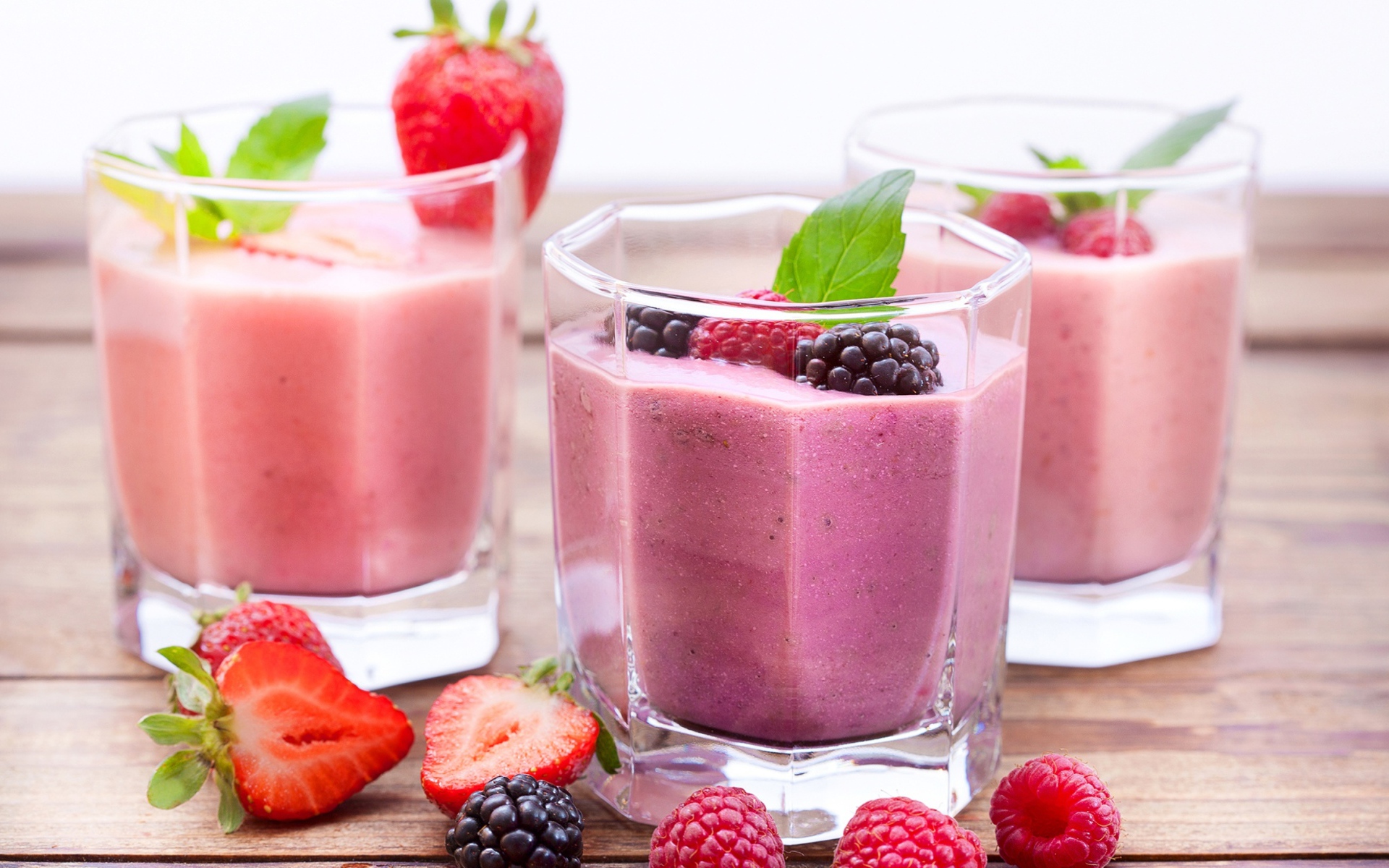 Ягодное смузи в стаканах на столе с ягодами малины, черники и клубники