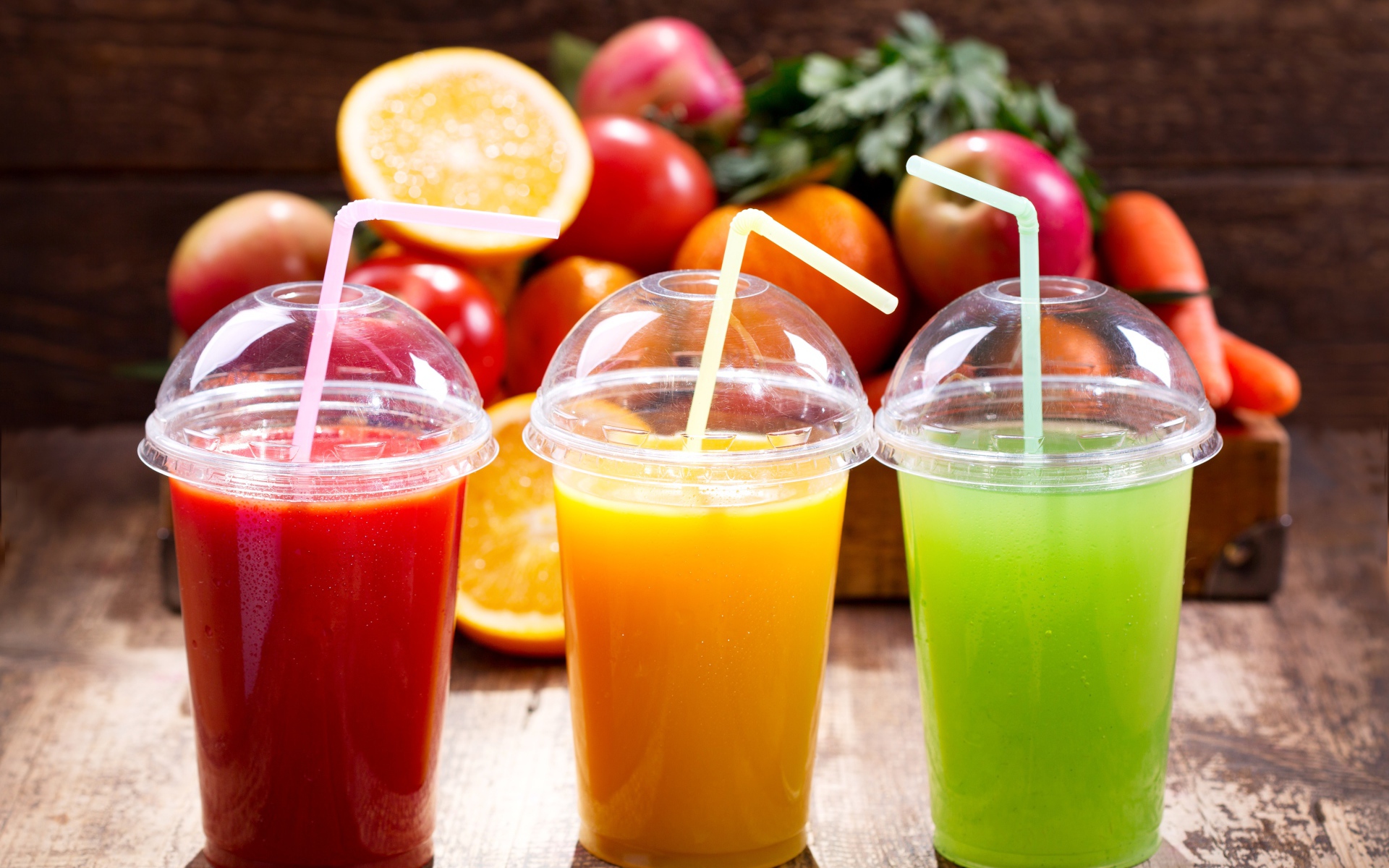 Свежие соки в стаканах с трубочками на столе