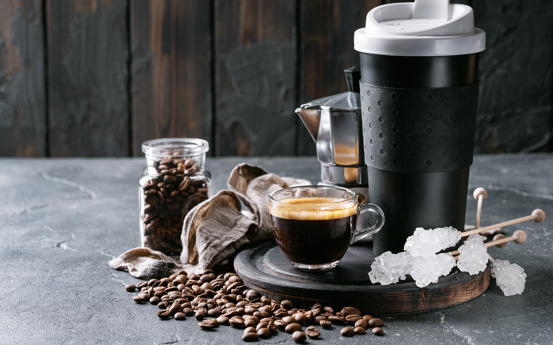 Стеклянная чашка кофе на столе с термосом и зернами